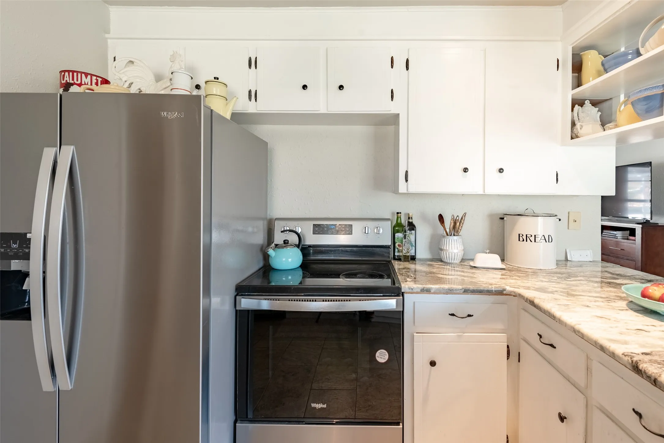 Kitchen with white cabinets, stainless steel appliances, and light stone counters