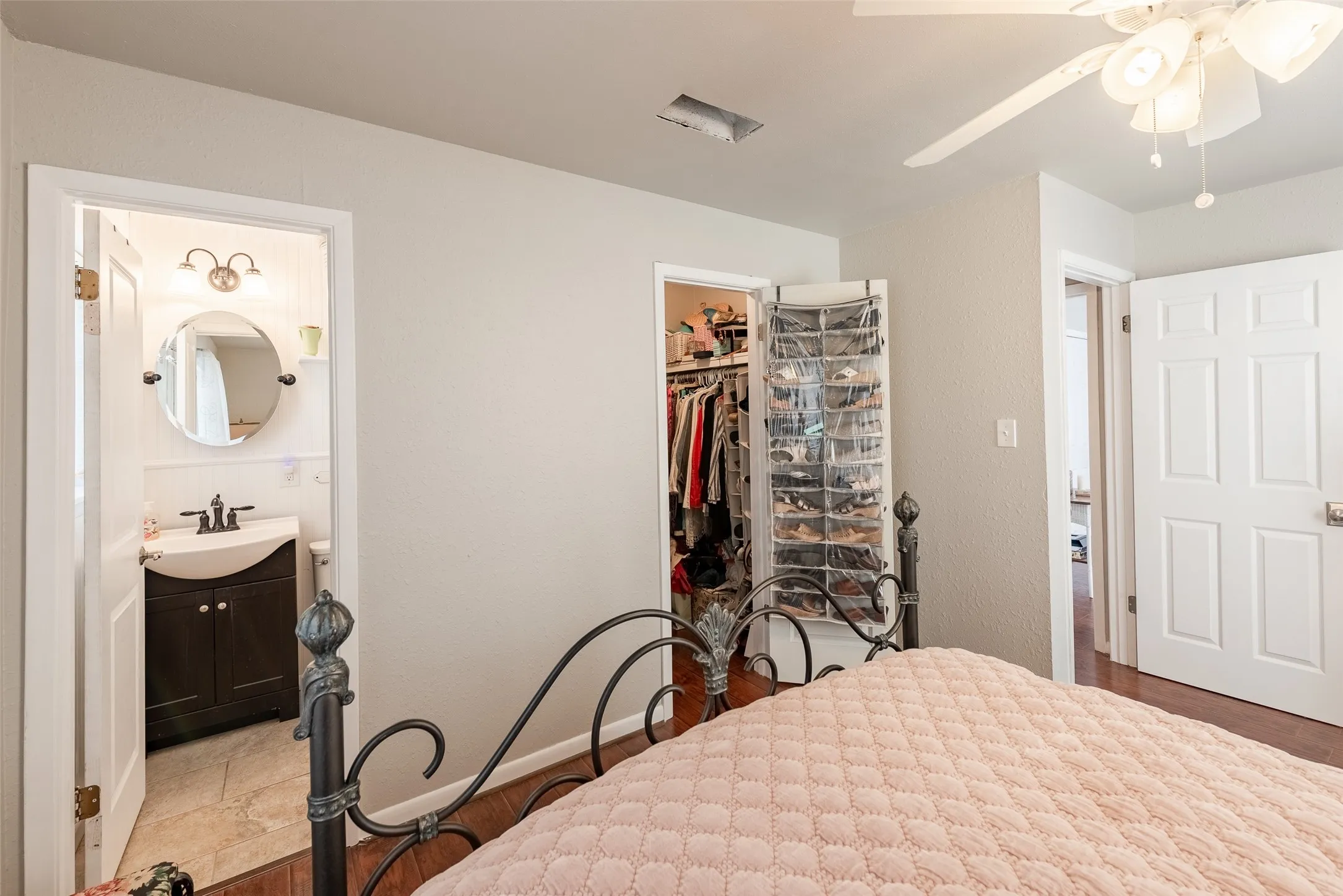 Bedroom featuring connected bathroom, ceiling fan, sink, light hardwood / wood-style flooring, and a closet