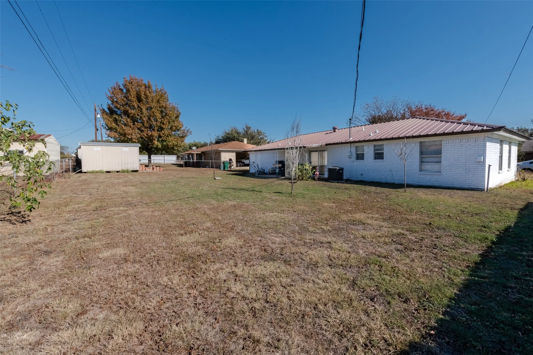 Rear view of property with central AC unit, a shed, and a yard