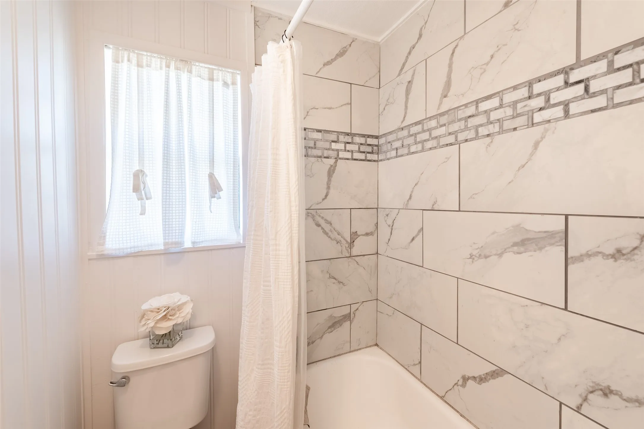 Bathroom featuring shower / bath combo, toilet, and plenty of natural light