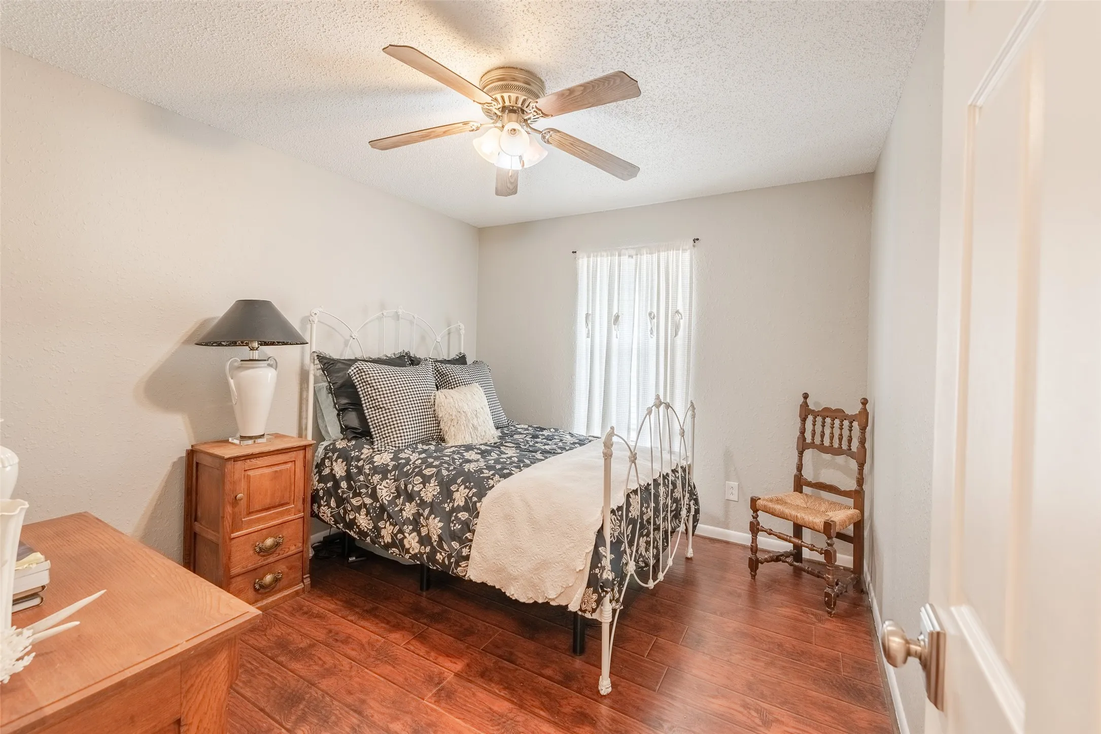 Bedroom with a textured ceiling, ceiling fan, and dark wood-type flooring