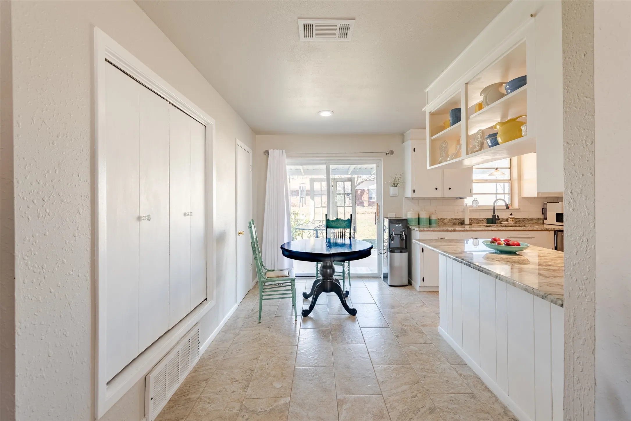 Kitchen with white cabinets, sink, light stone counters, and backsplash