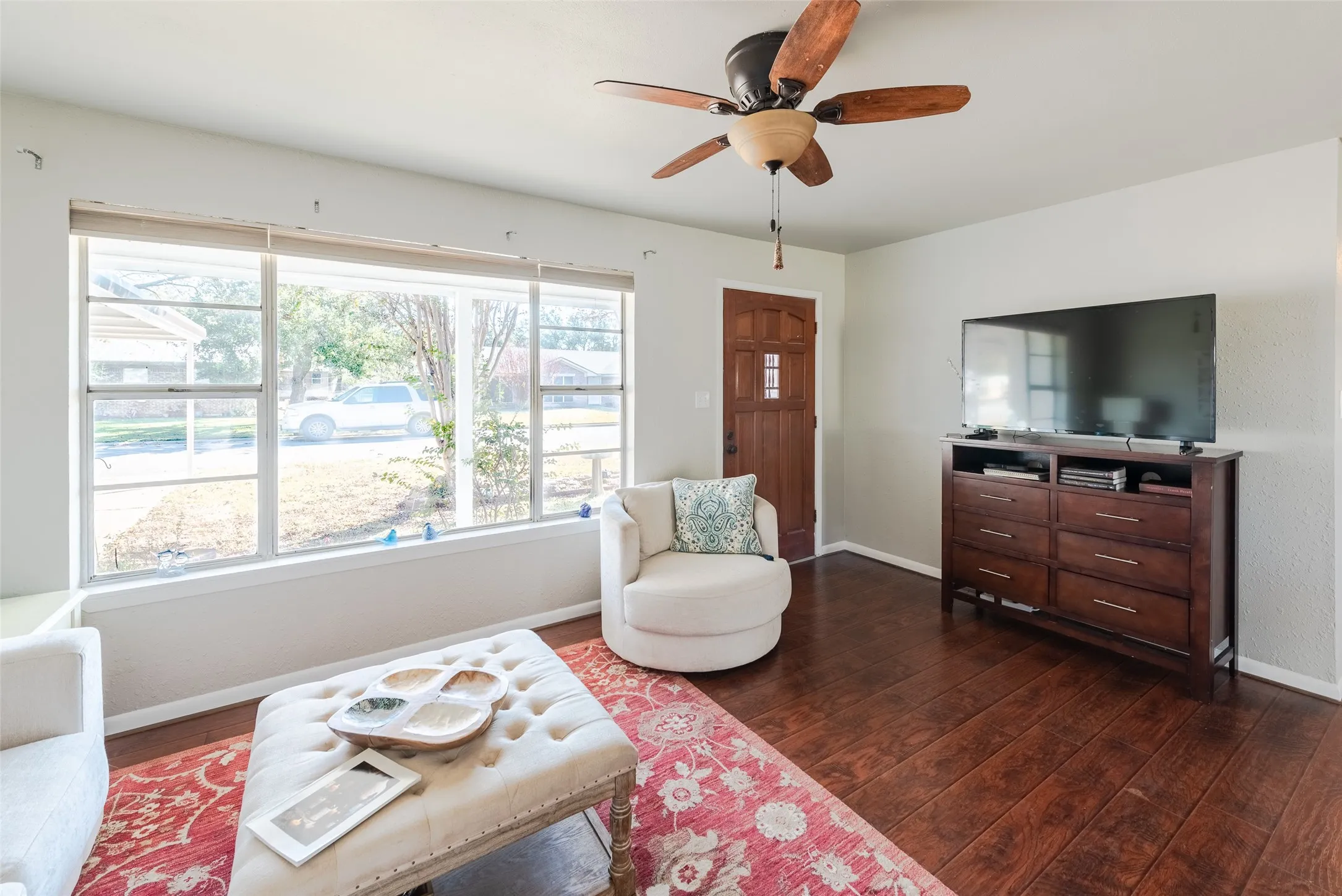 Living room featuring ceiling fan and dark wood-type flooring