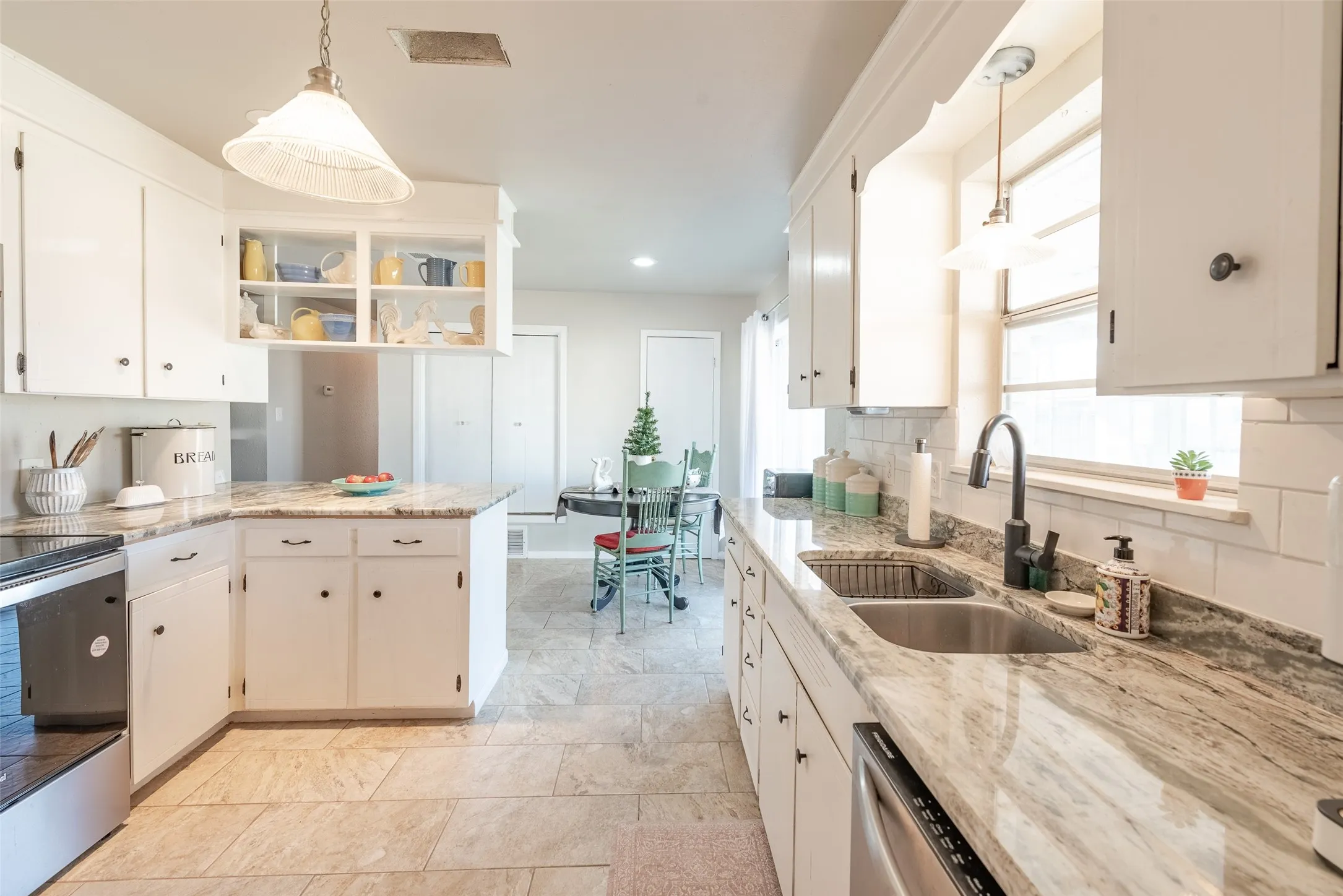Kitchen with sink, white cabinets, pendant lighting, and appliances with stainless steel finishes