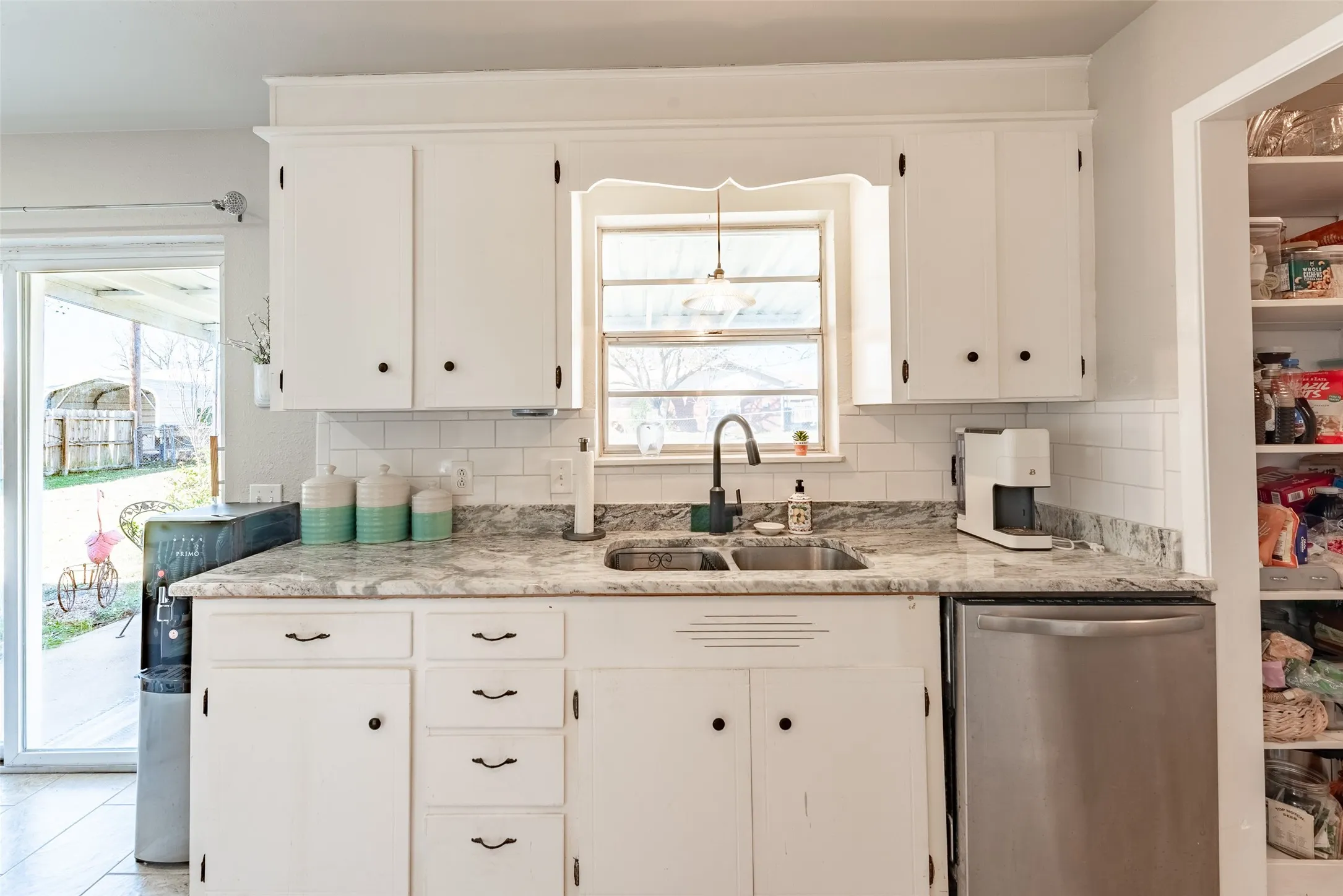 Kitchen with dishwasher, white cabinetry, and sink