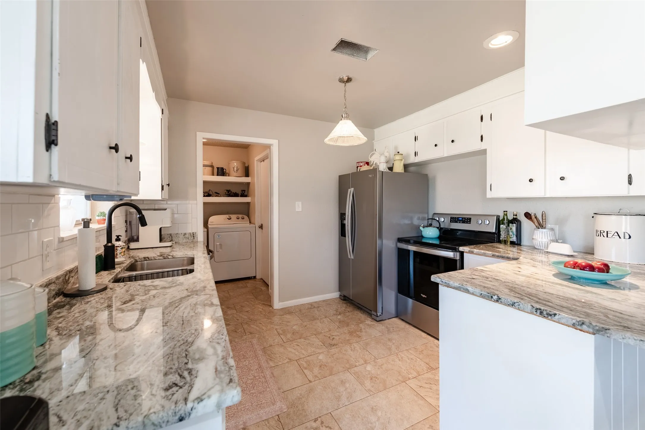 Kitchen with washer / dryer, white cabinetry, decorative light fixtures, and appliances with stainless steel finishes