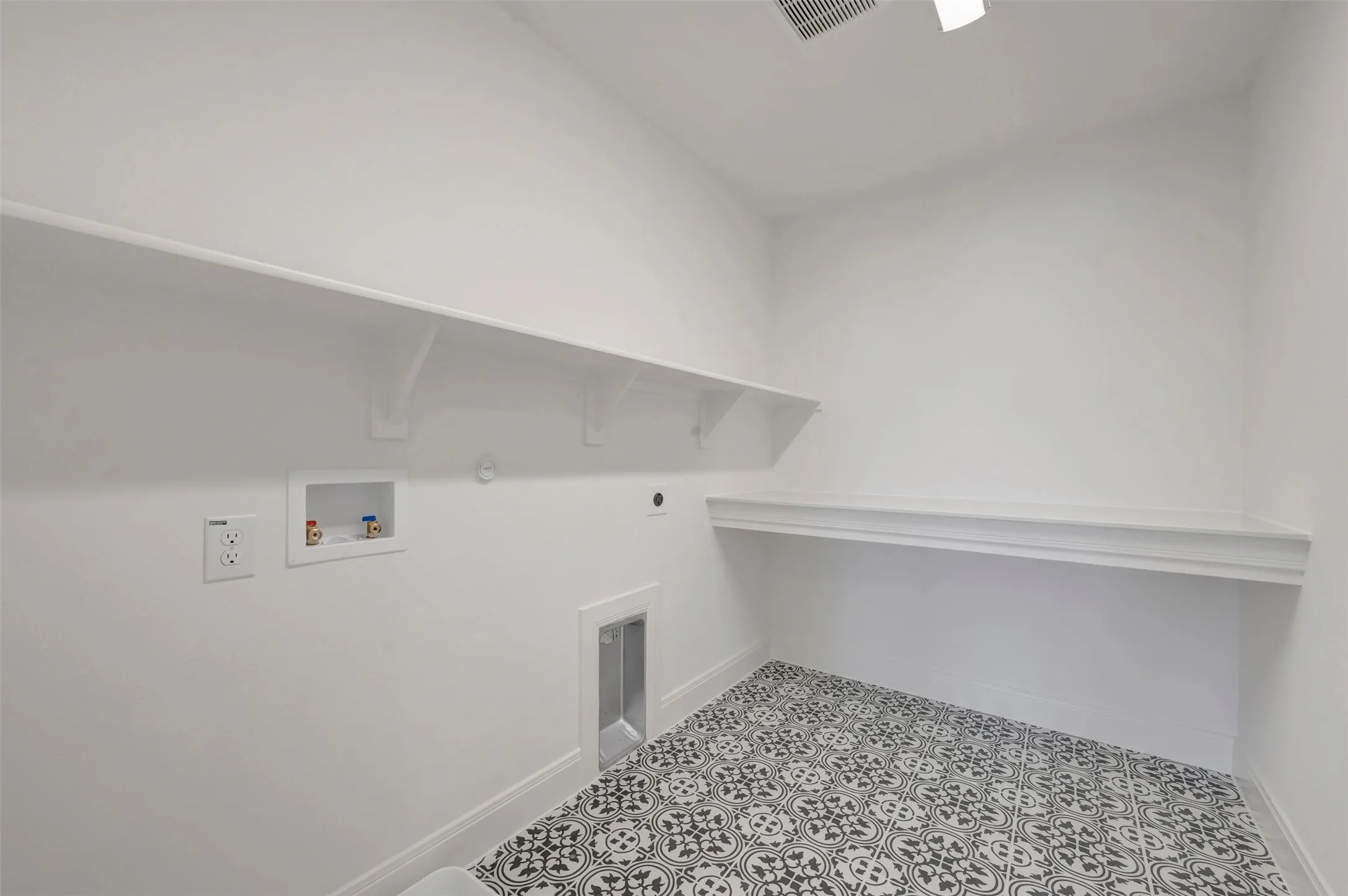 Utility room featuring patterned floor tile, white walls, and built-in shelving