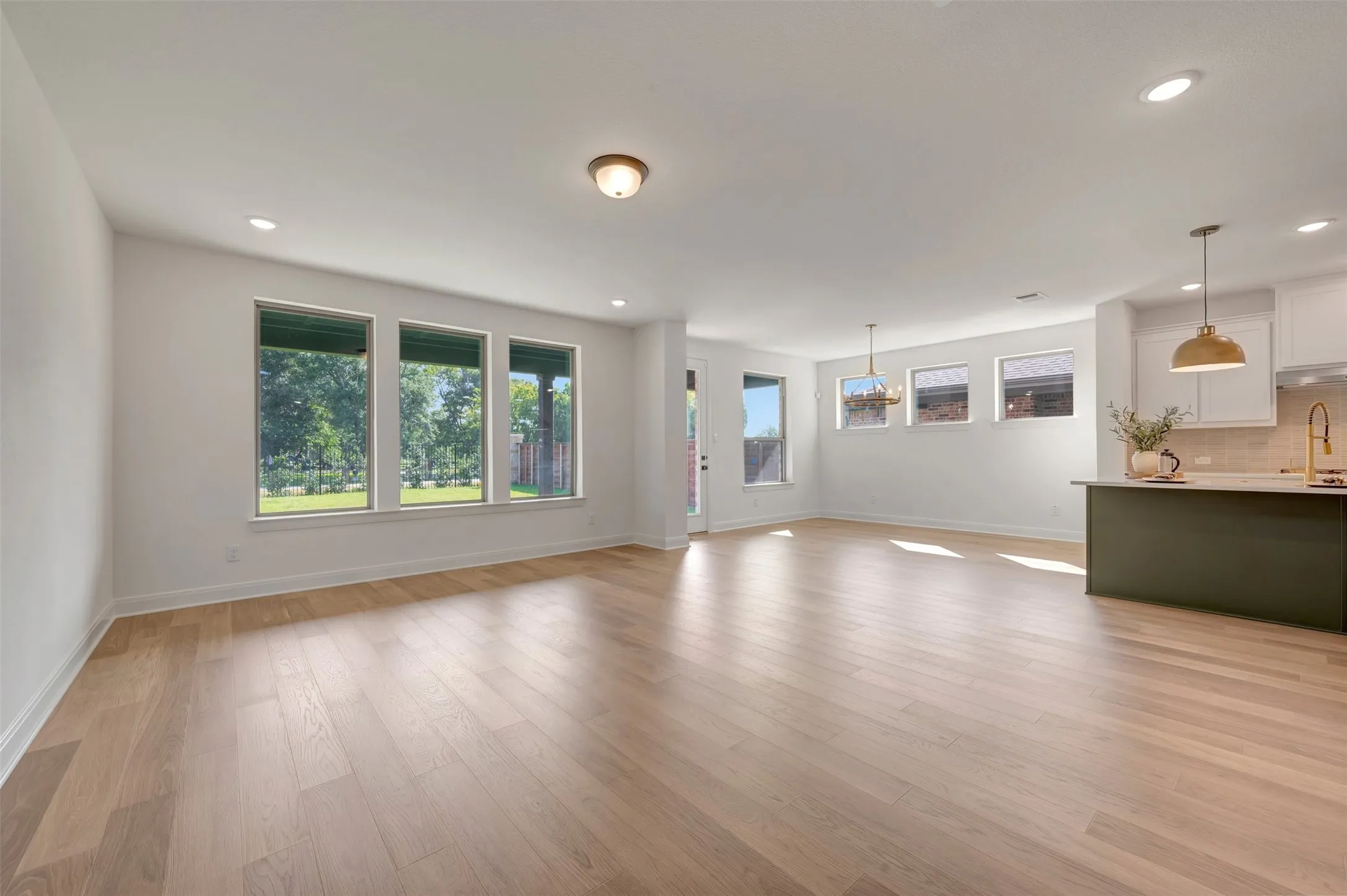 Spacious open-concept living area featuring wood-finish flooring, recessed lighting, and multiple windows