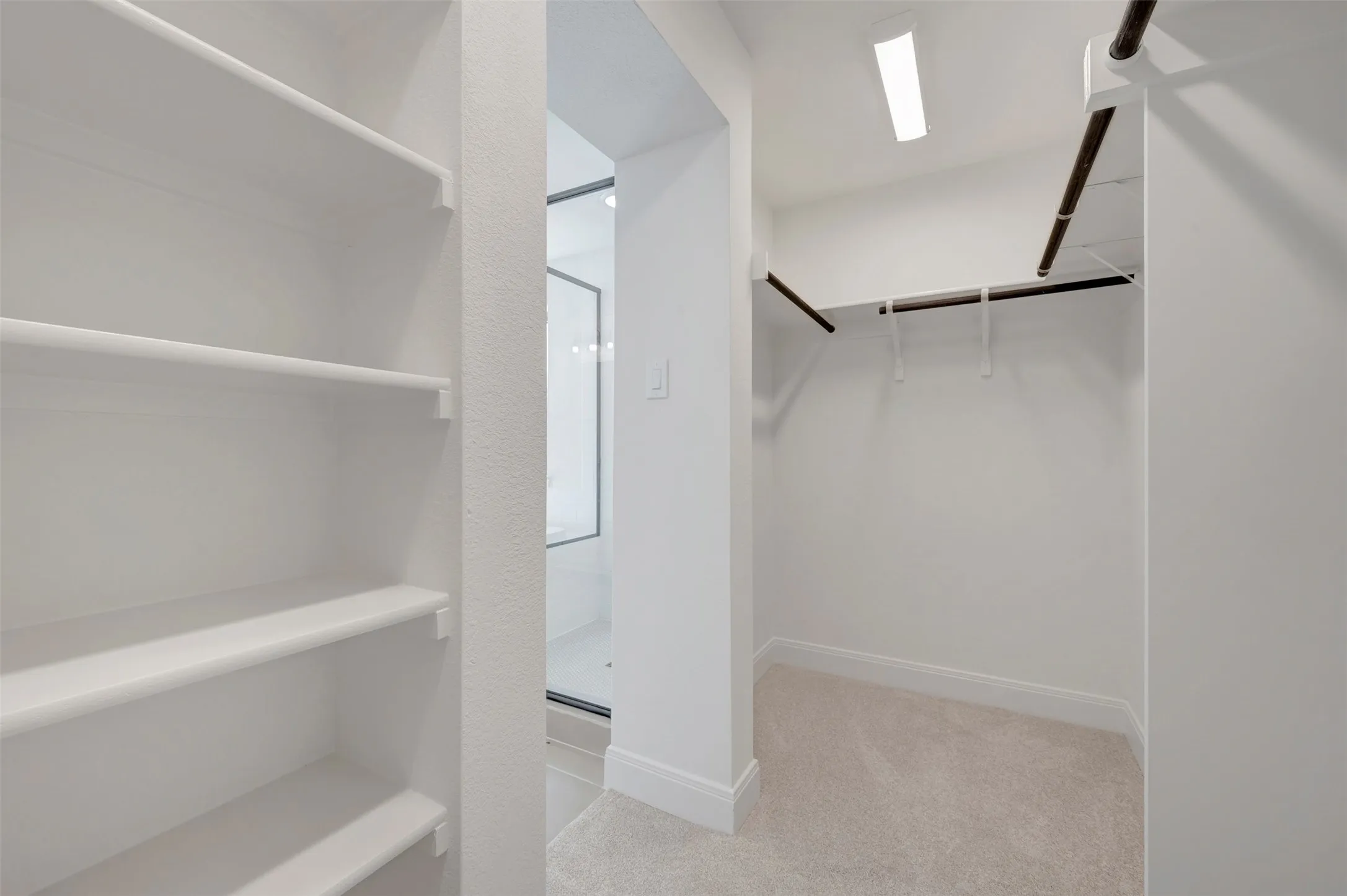 Spacious walk-in closet featuring built-in shelving, dual clothing rods, recessed lighting, and neutral carpeting