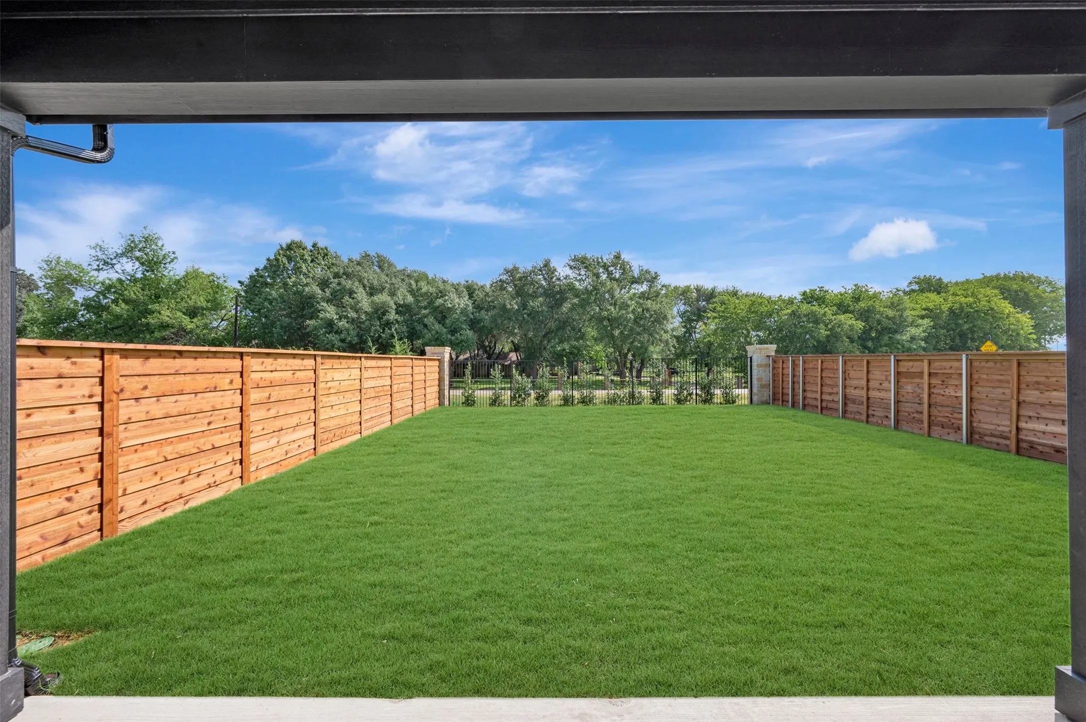 Expansive backyard featuring a lush lawn, new horizontal privacy fencing, and concrete patio flooring