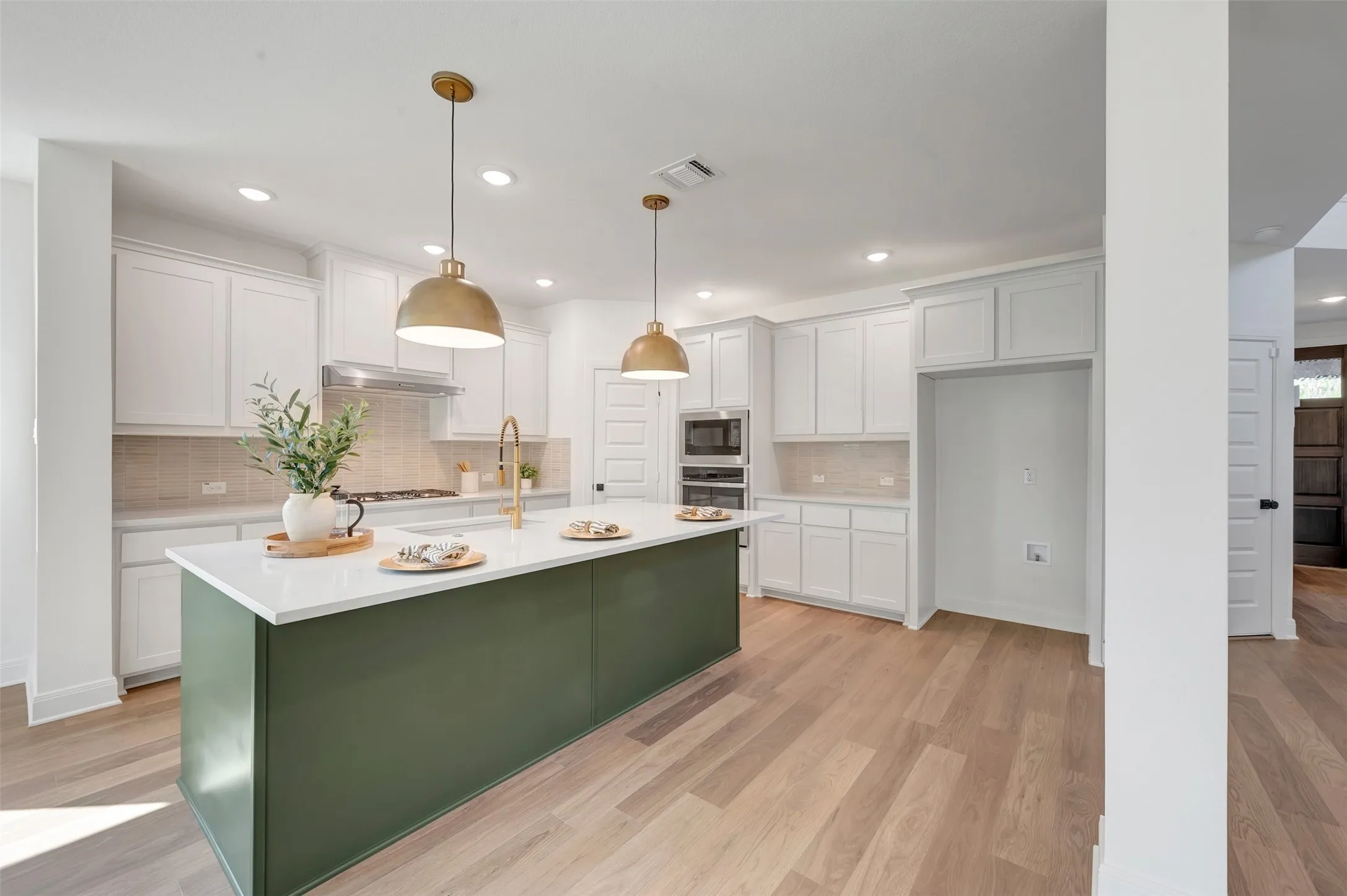 Kitchen featuring a large green island with a white countertop, recessed lighting, and two brass pendant lights