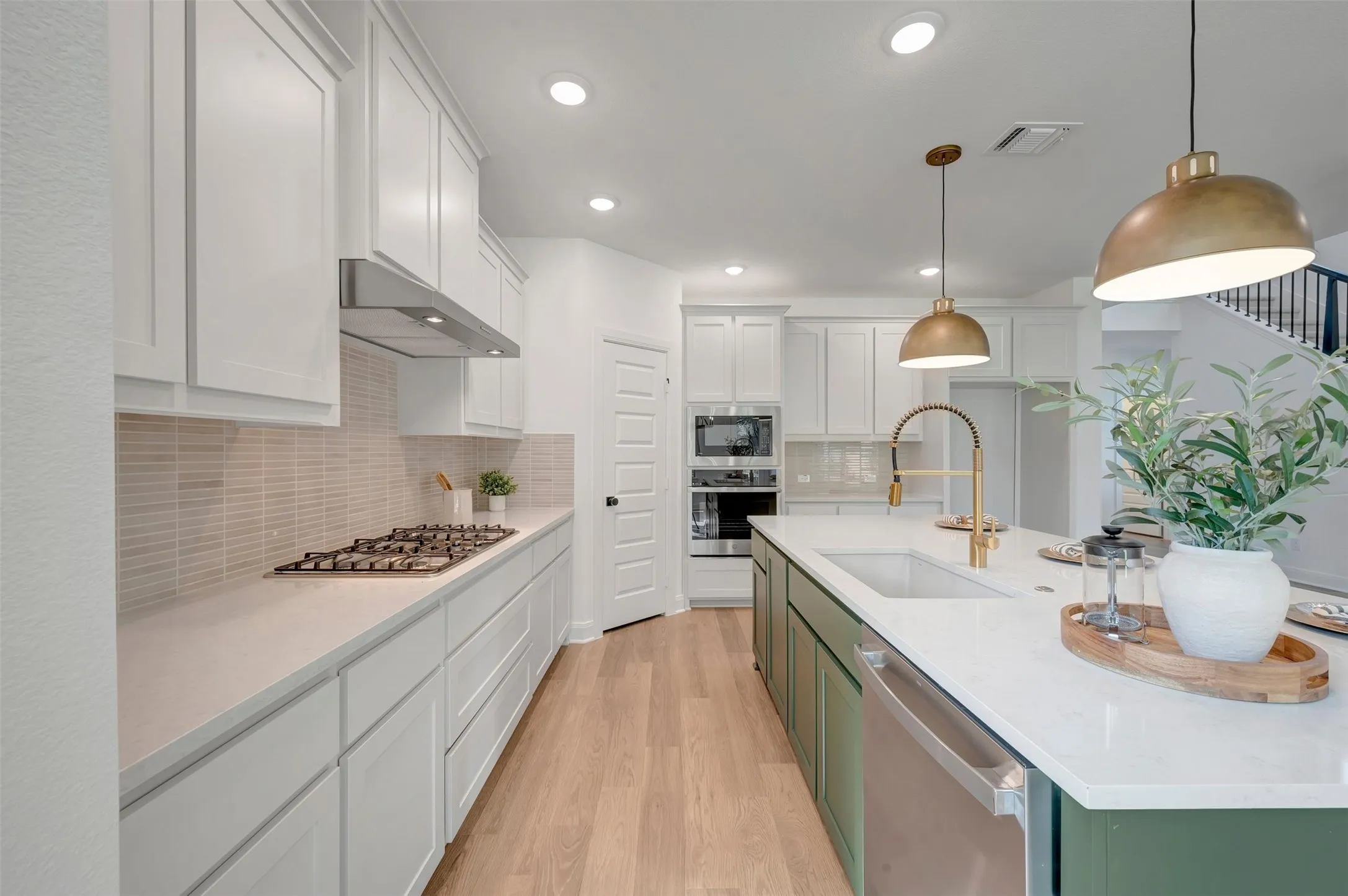 Modern kitchen featuring a large central island with a single-basin sink and brass gooseneck faucet