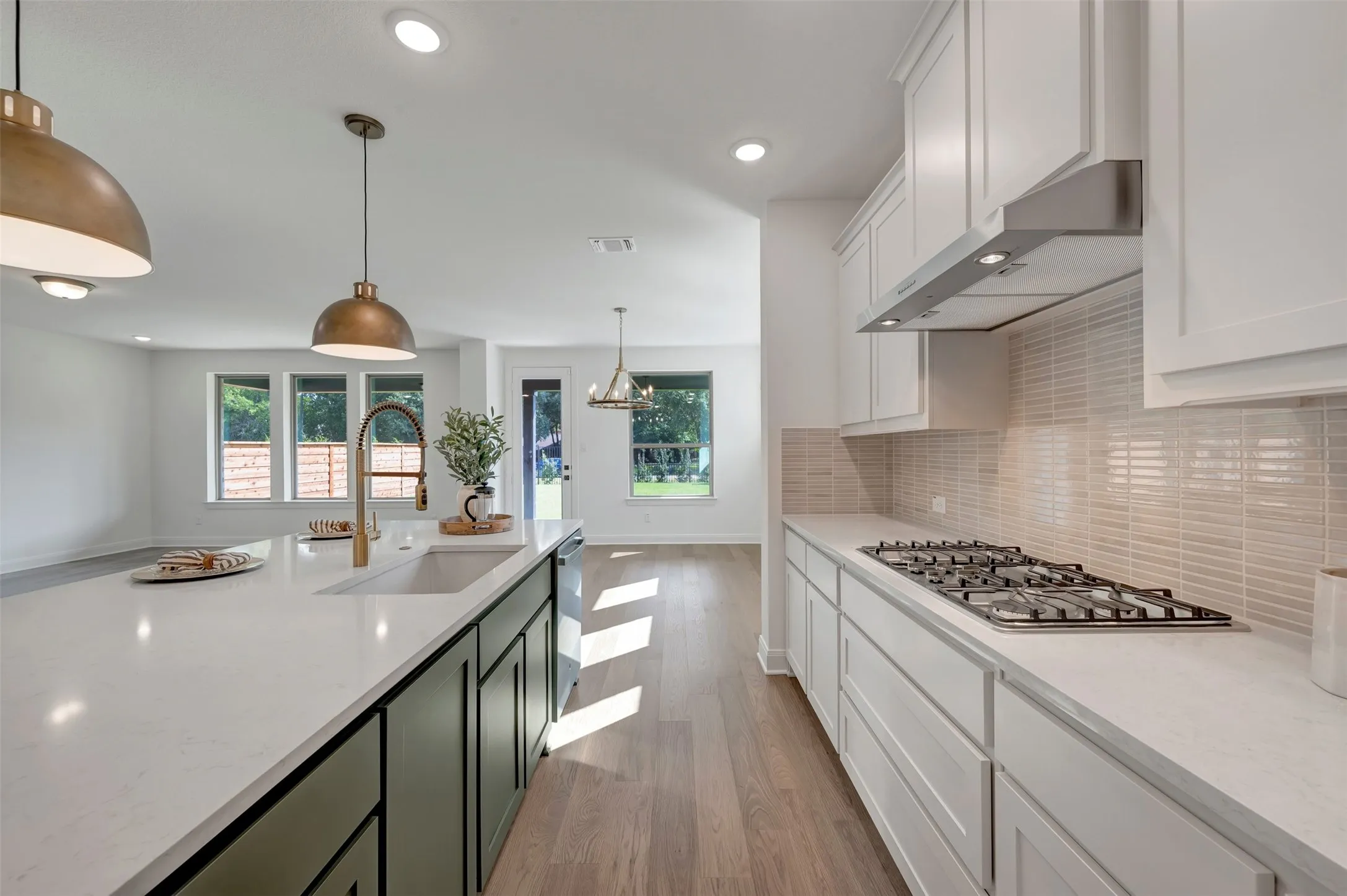 Modern kitchen featuring white cabinetry with shaker-style doors, white subway tile backsplash, and stainless steel appliances including a six-burner gas cooktop