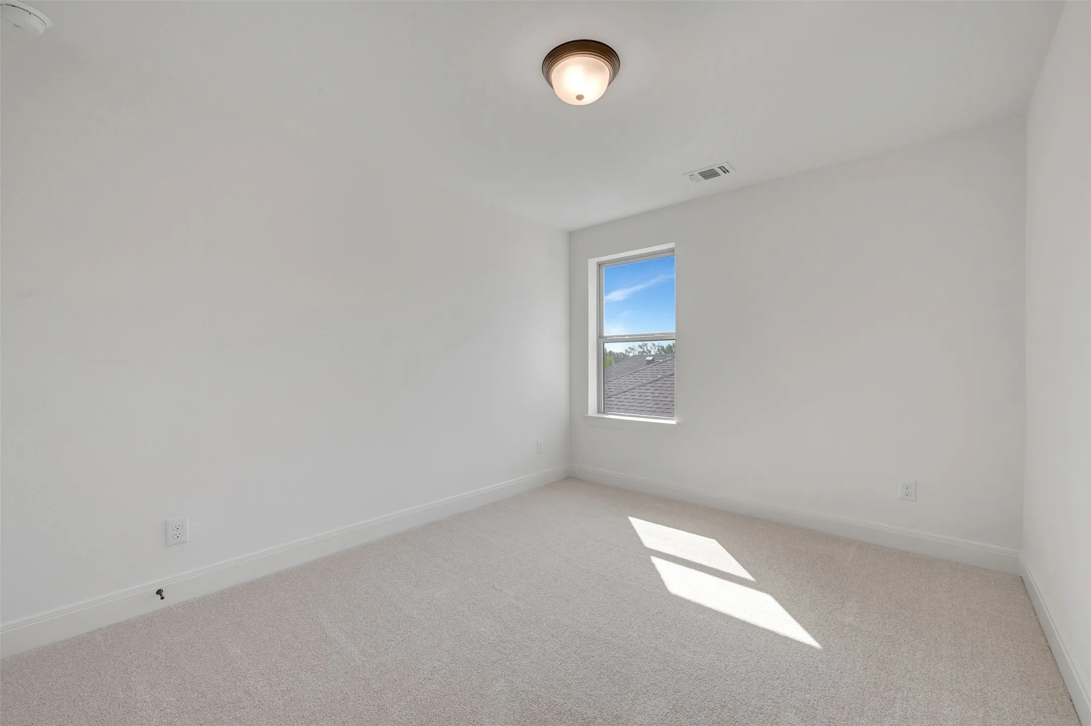 Carpeted room with a single window and neutral wall tones