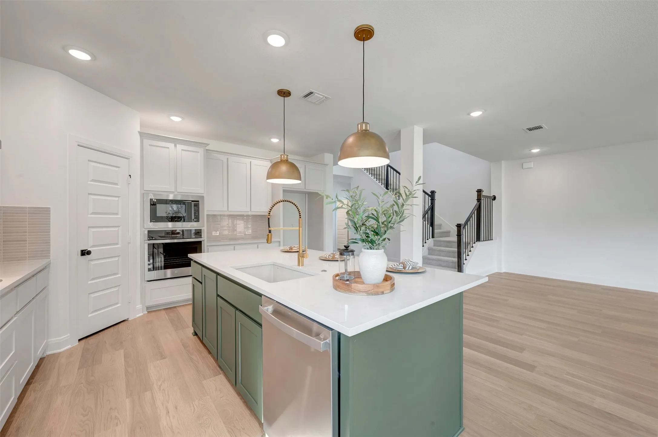 Kitchen island featuring a white countertop, undermount sink, and green base cabinetry