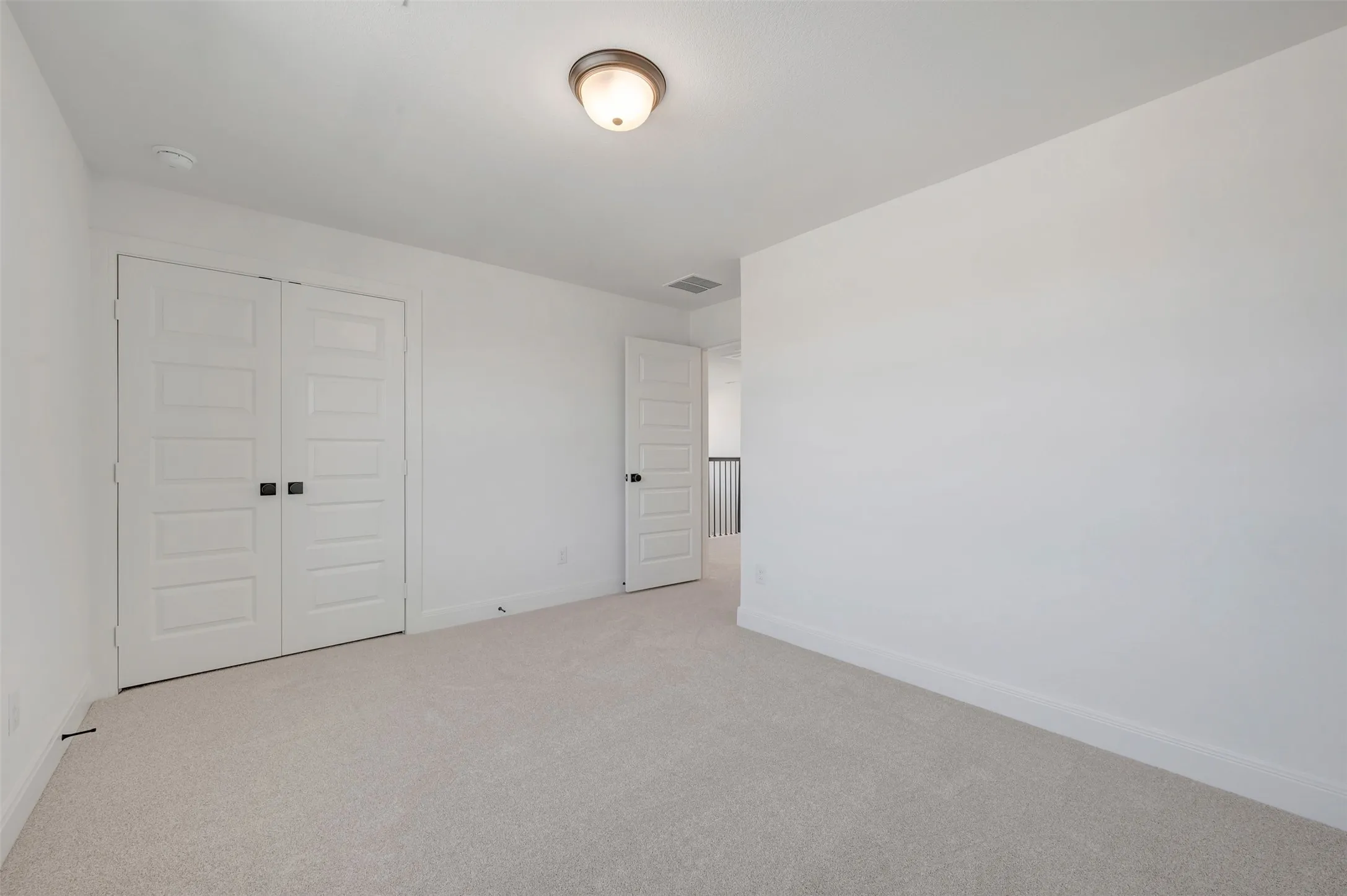 Spacious bedroom with neutral carpet flooring, dual white six-panel closet doors, and soft recessed ceiling lighting