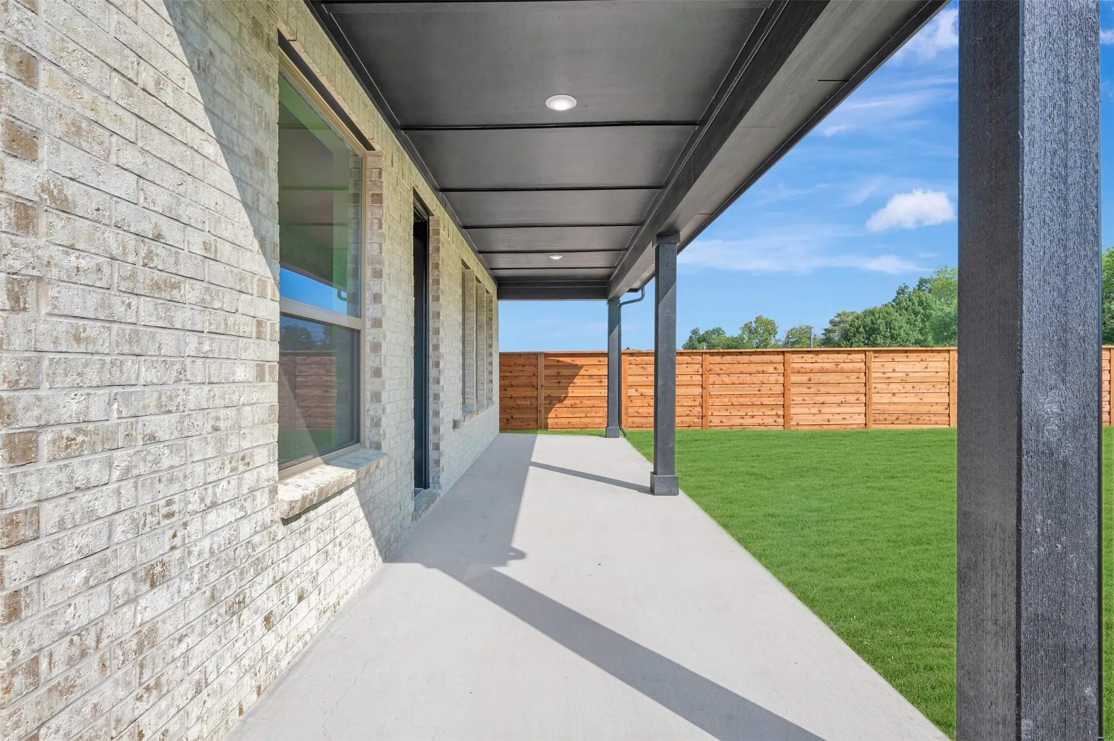 Covered patio with recessed lighting, concrete flooring, and a full-height privacy fence