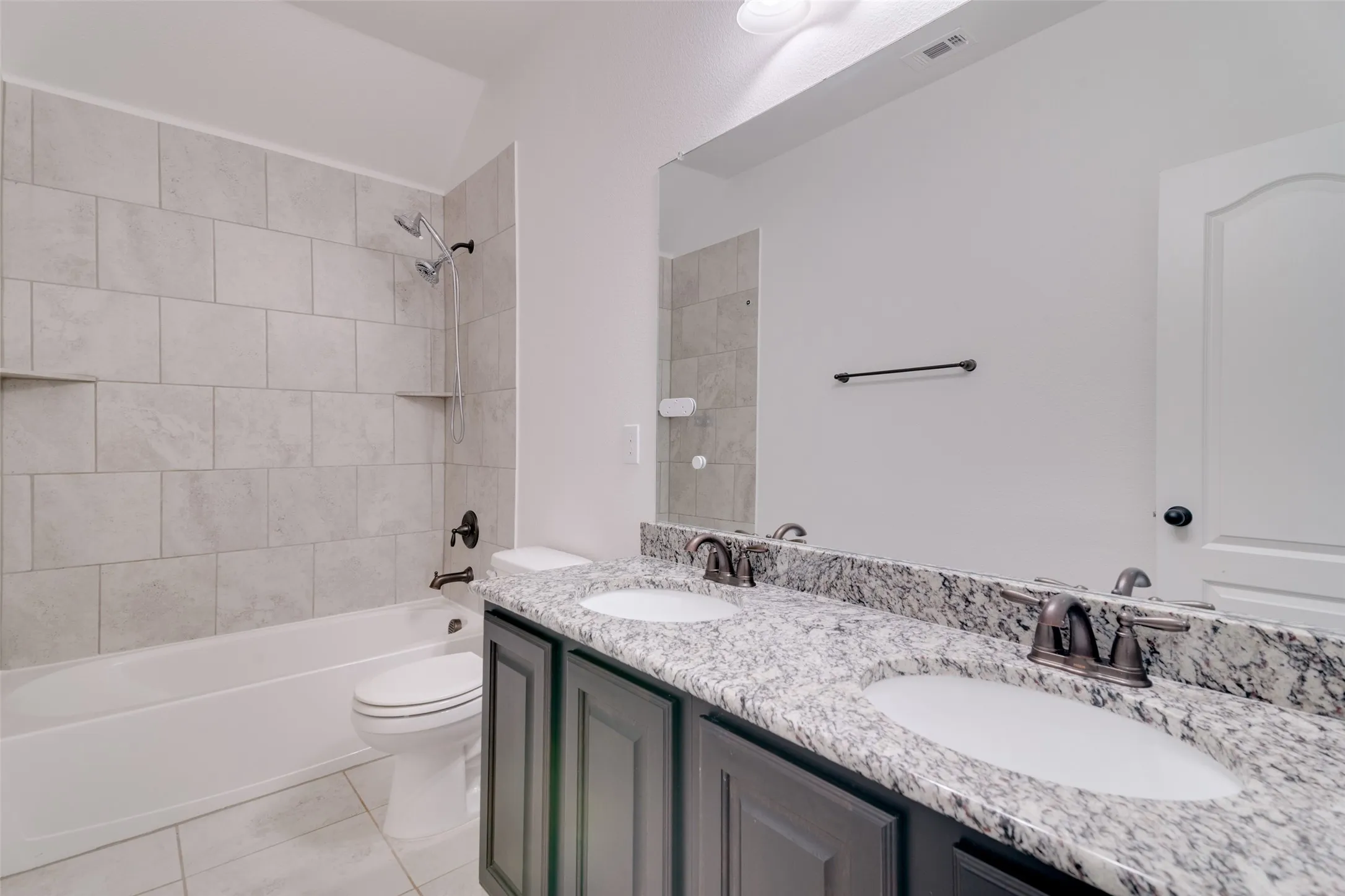Full bath with double vanity, bathtub / shower combination, and light tile patterned flooring