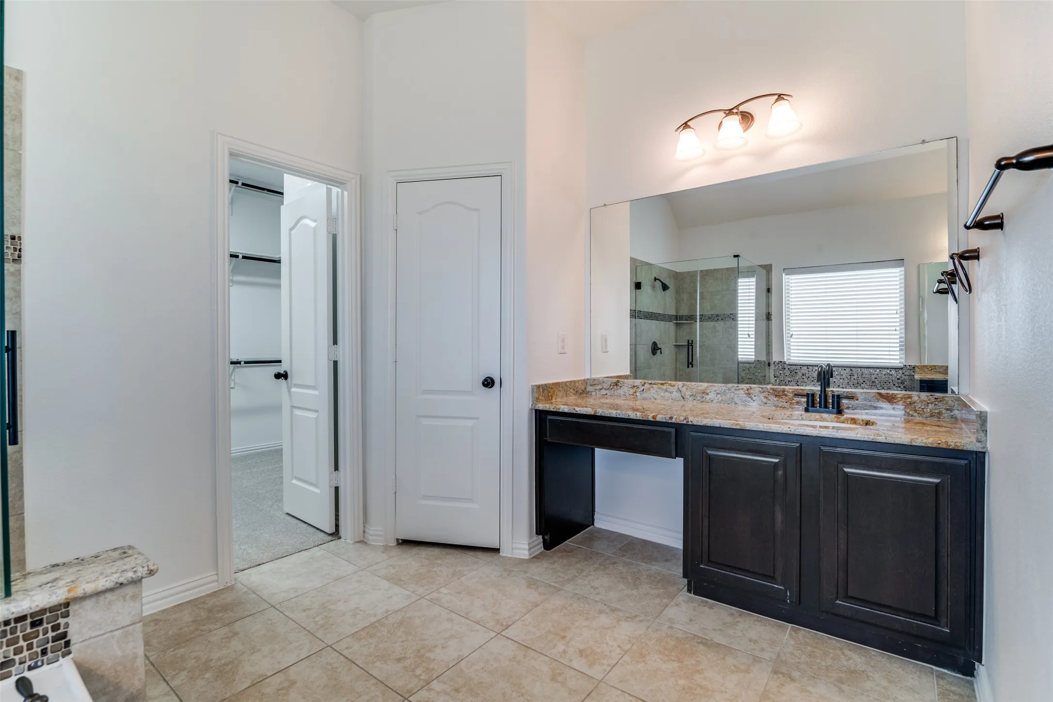 Full bath with separate tub and shower, one of the vanities, a spacious closet, and light tile patterned floors