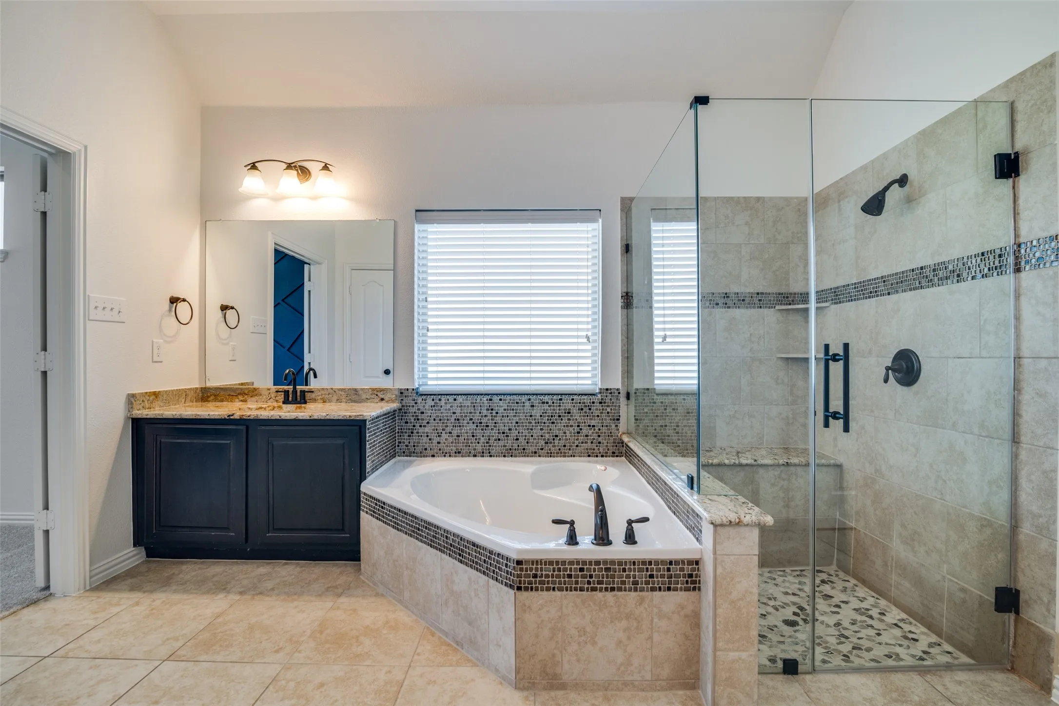 View of the other vanity, soaking tub, and separate shower with frameless glass door