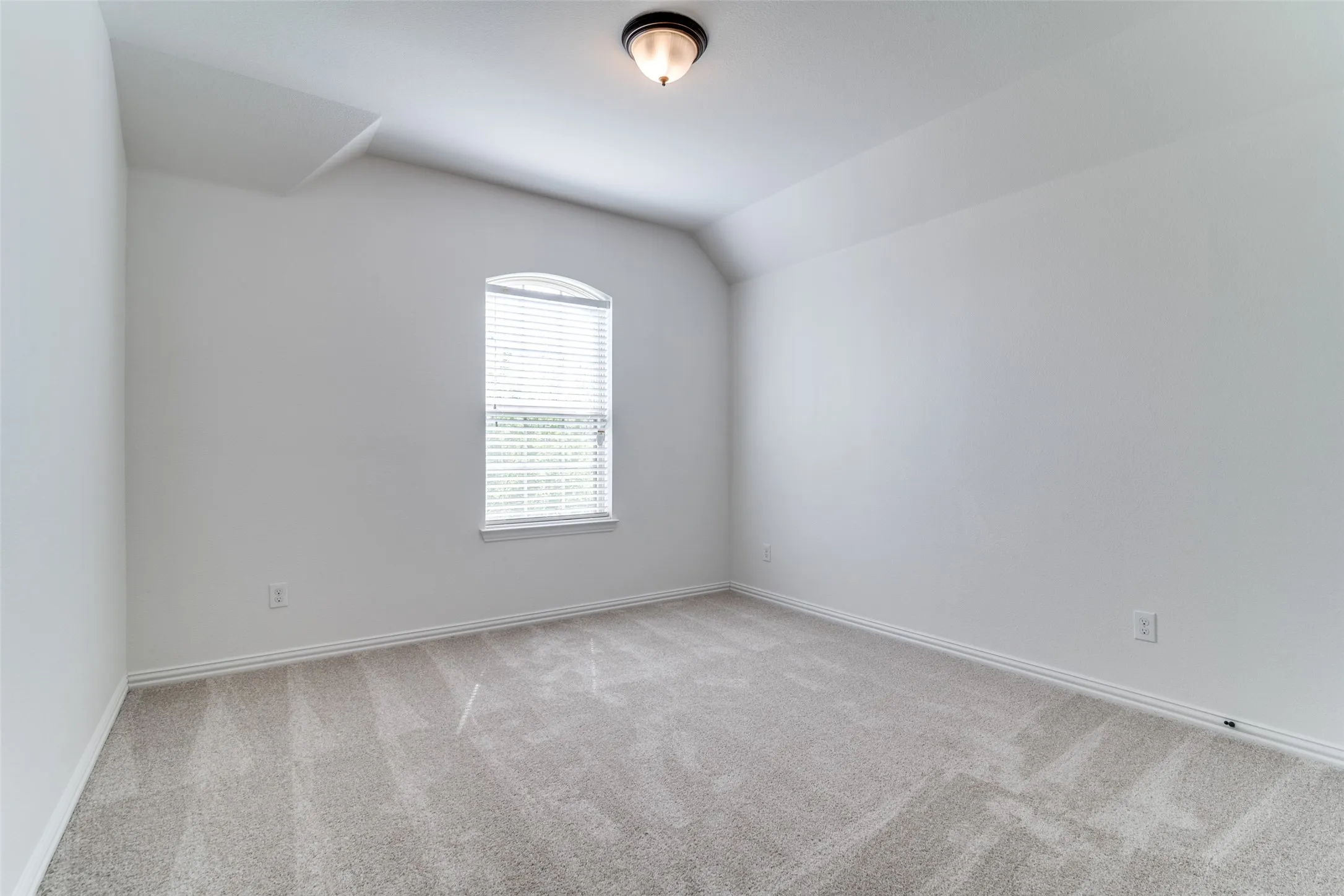 Upstairs bedroom #2 with light colored carpet and vaulted ceiling