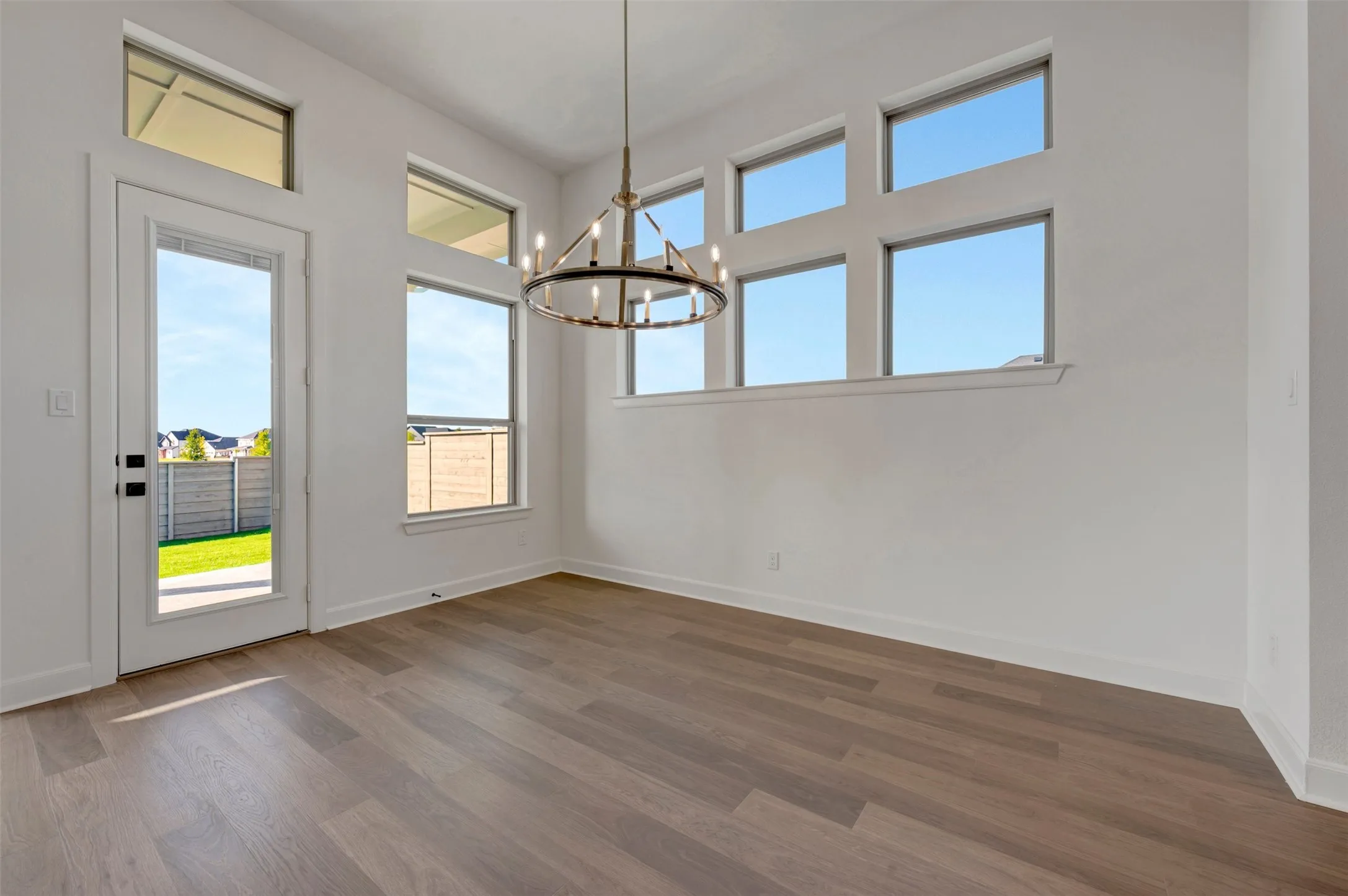 Room featuring high ceilings, wood-finish flooring, and white walls