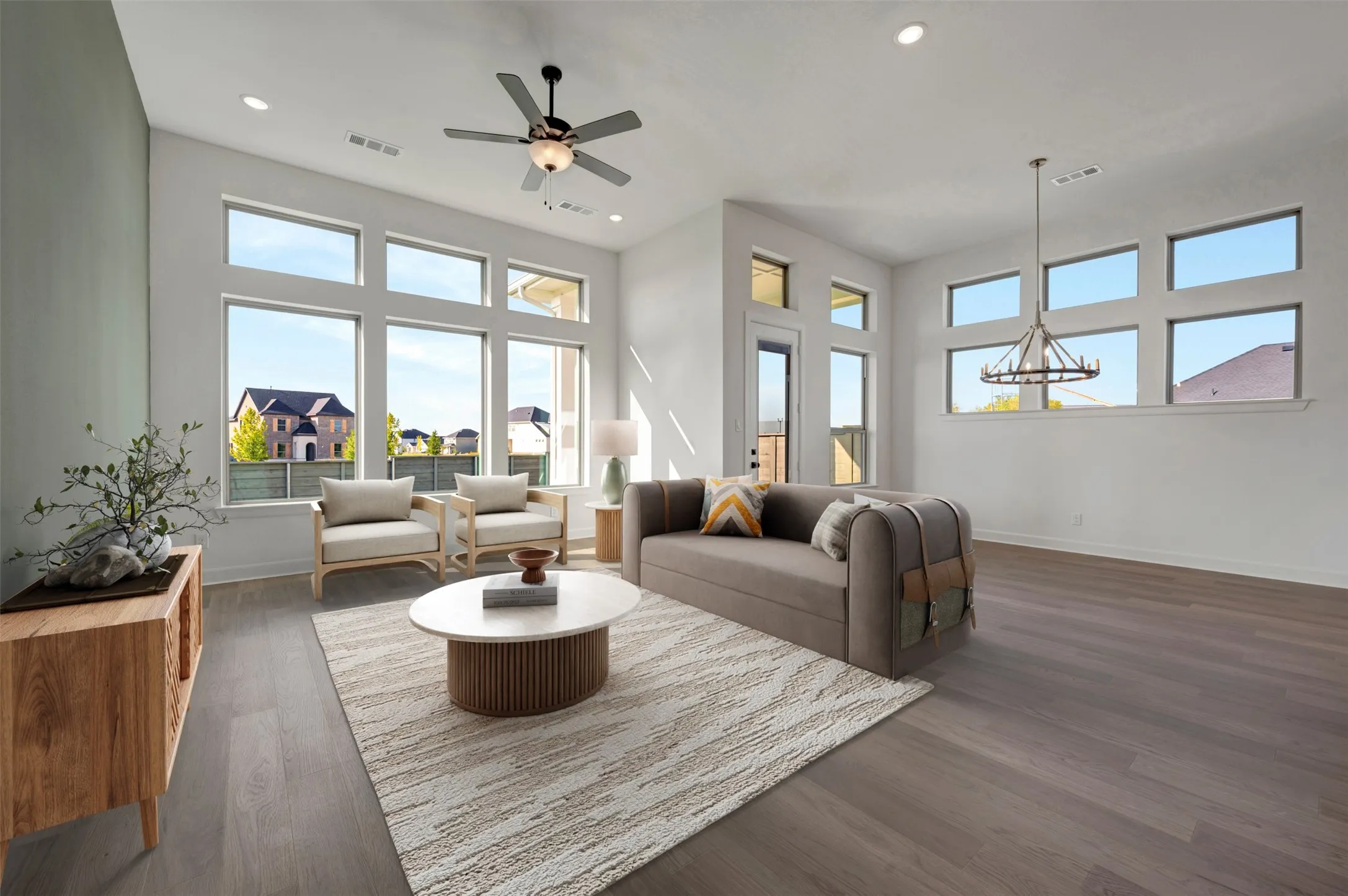 Spacious living area featuring extensive window arrays, high ceilings with recessed lighting, a modern ceiling fan, and wood-finish flooring