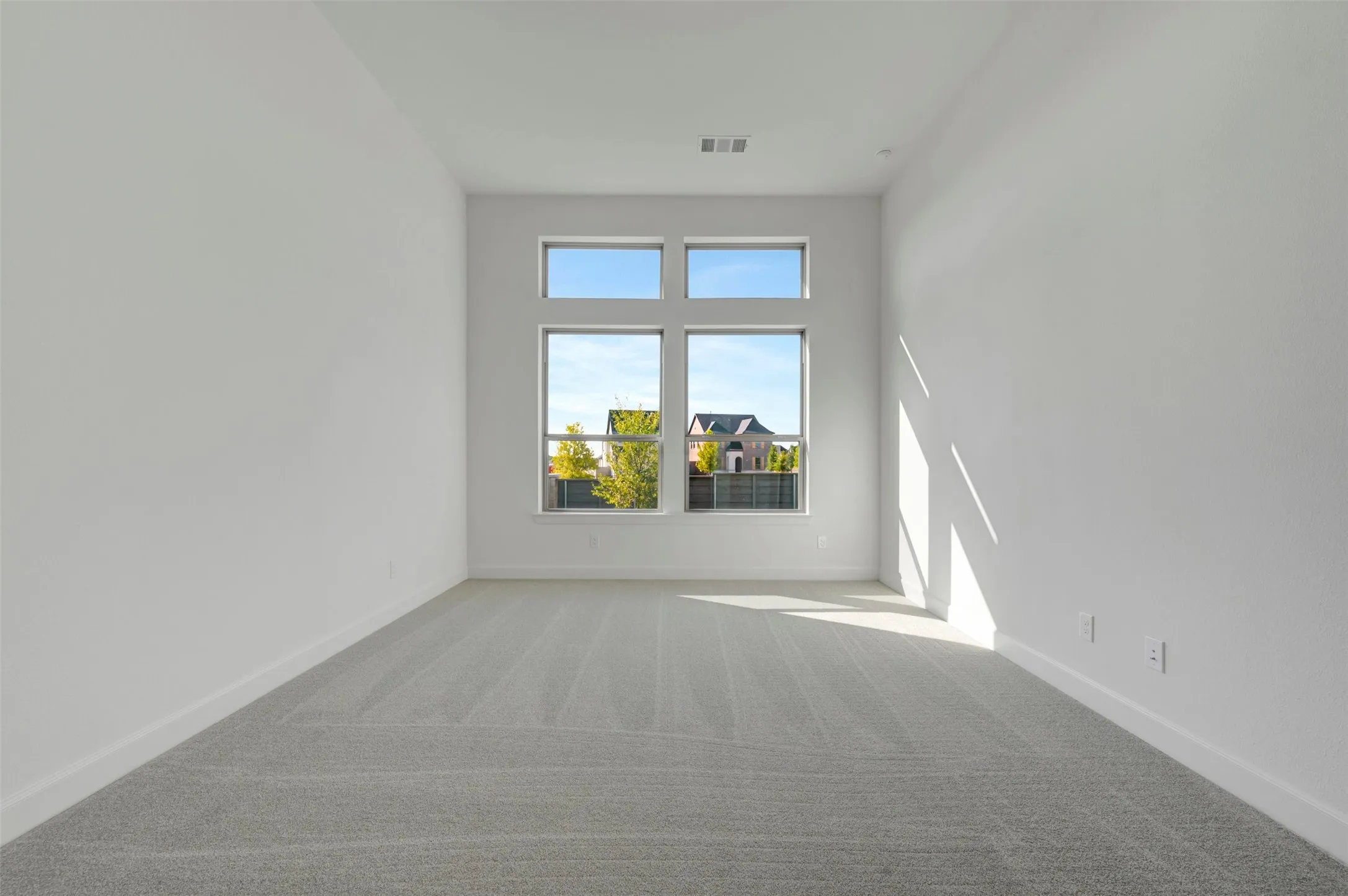 Room featuring light gray patterned carpeting, white baseboards, and white walls