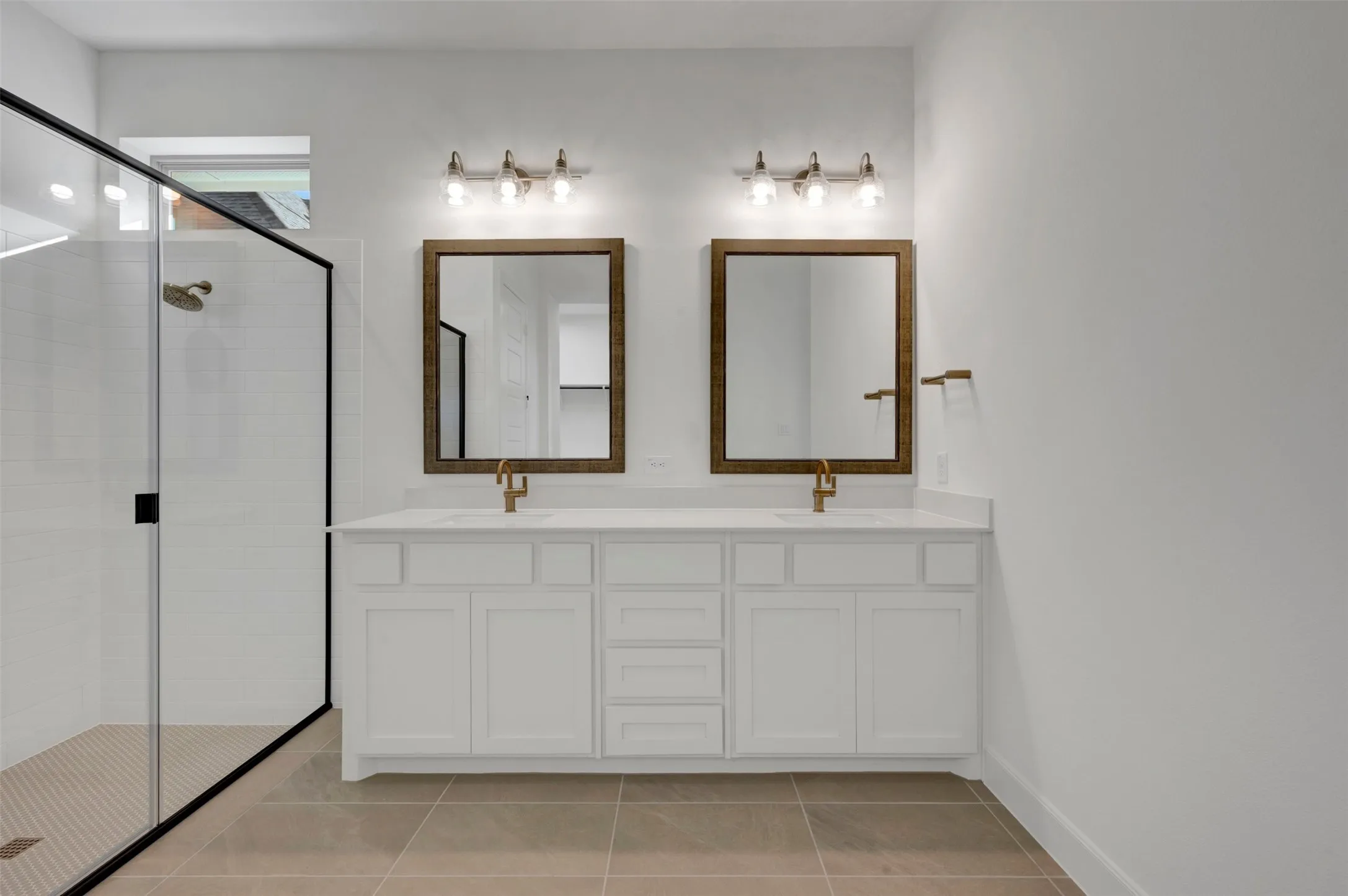Bathroom featuring a dual vanity with white cabinetry, white countertop, and brass-finish fixtures