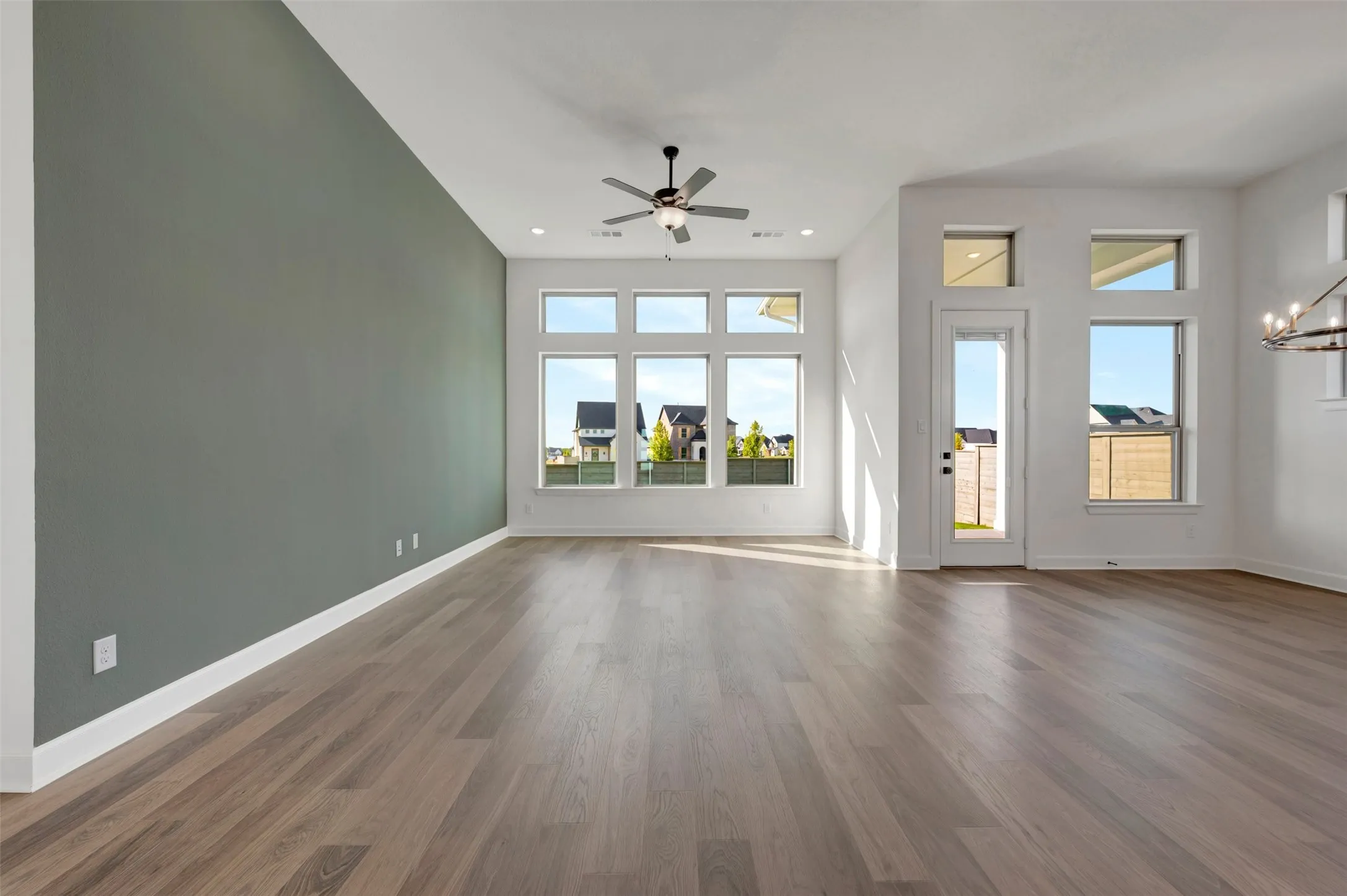 Spacious room featuring wood-finish flooring, a contemporary ceiling fan, and recessed lighting