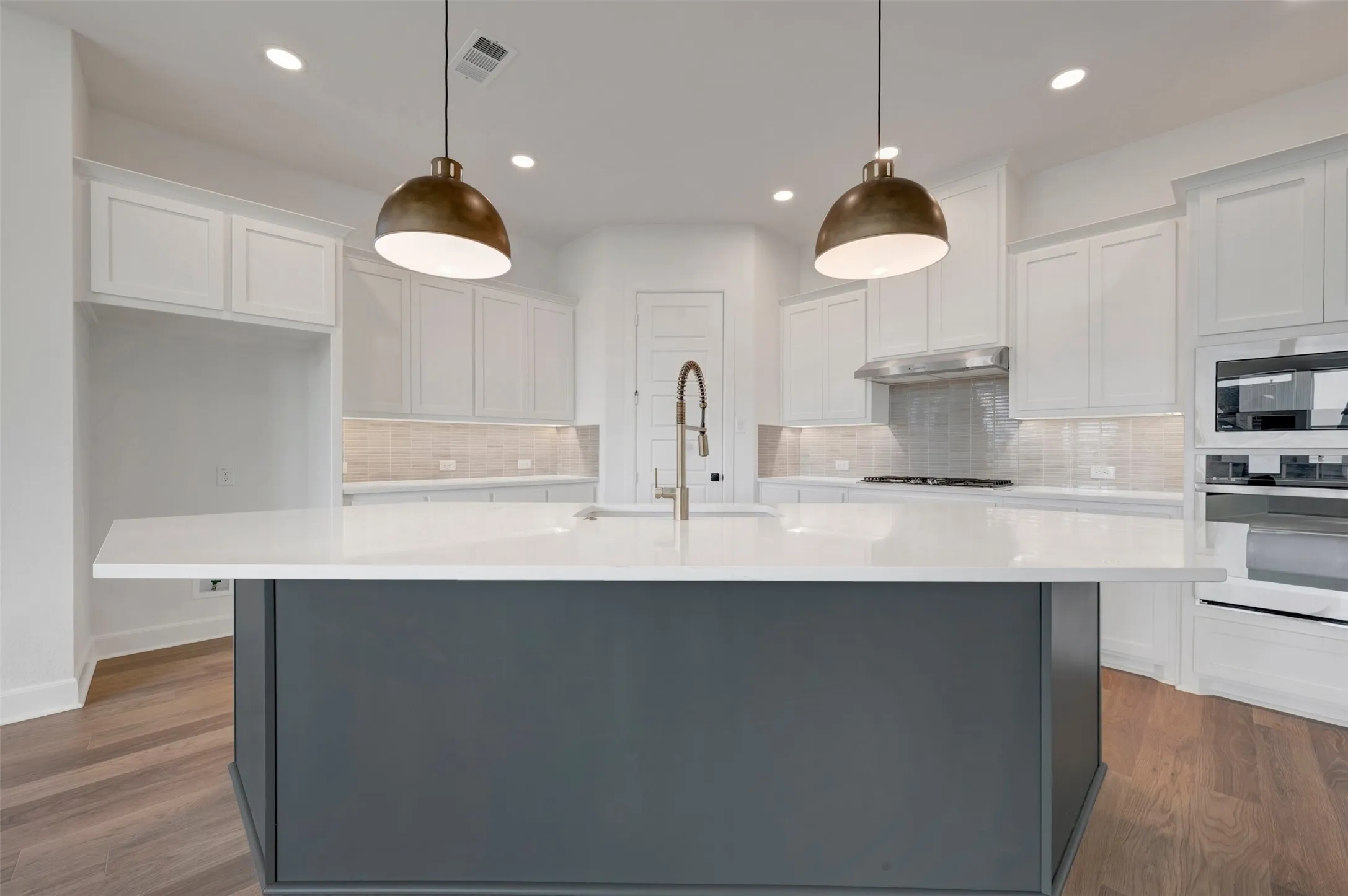 Kitchen island with white countertop and integrated sink, complemented by two pendant light fixtures