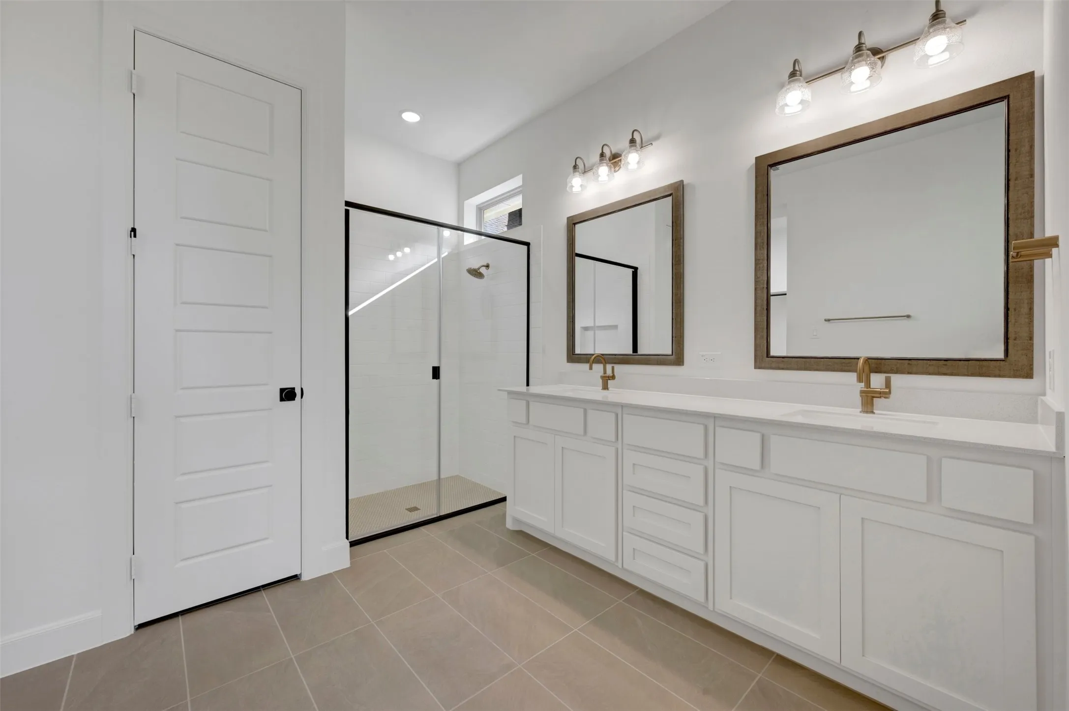 Double vanity featuring white cabinetry, light countertops, and brass-finish fixtures