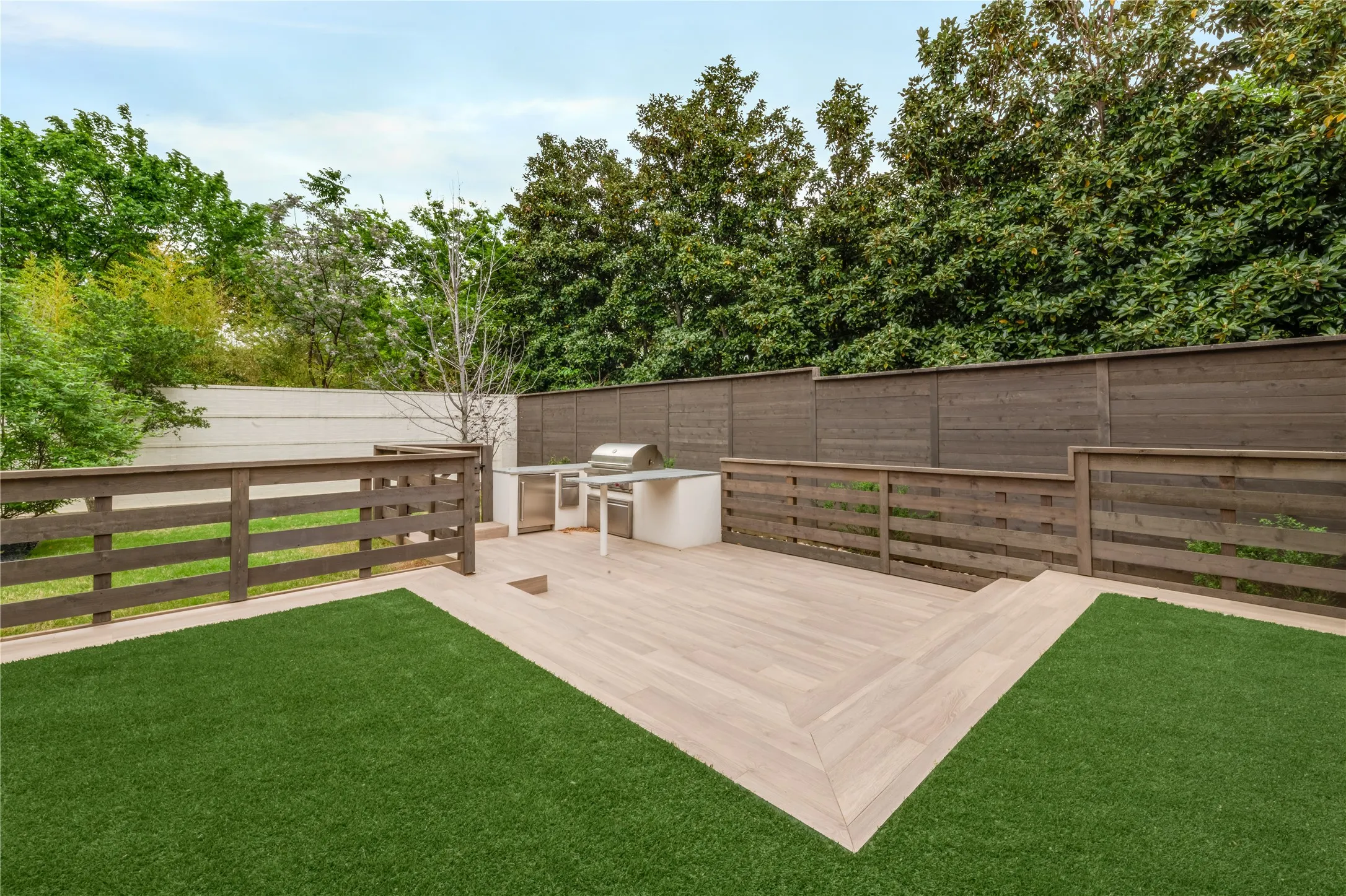 Backyard with turf and custom deck including outdoor kitchen