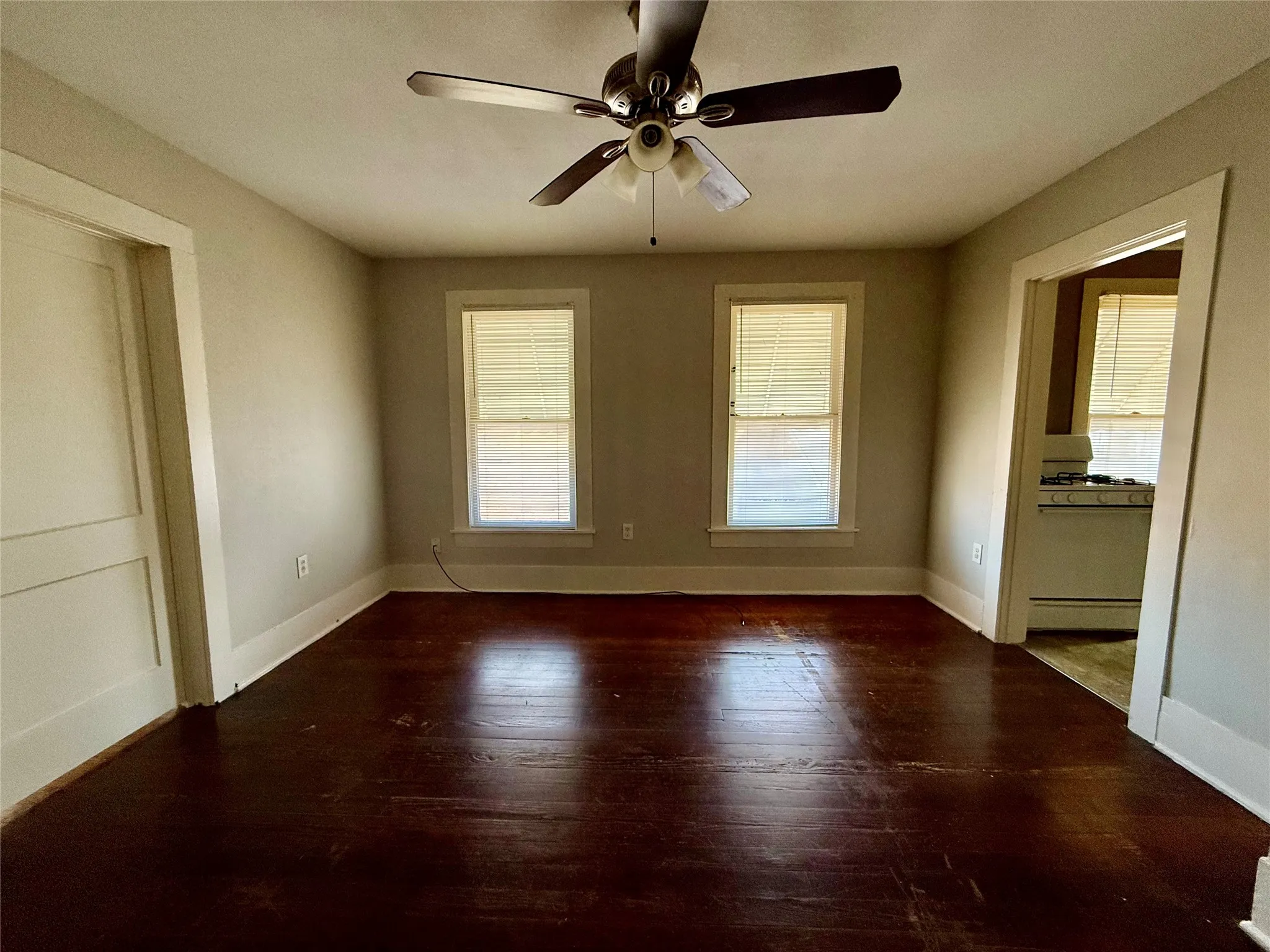 Unfurnished room featuring ceiling fan, dark wood-type flooring, and a baseboard radiator