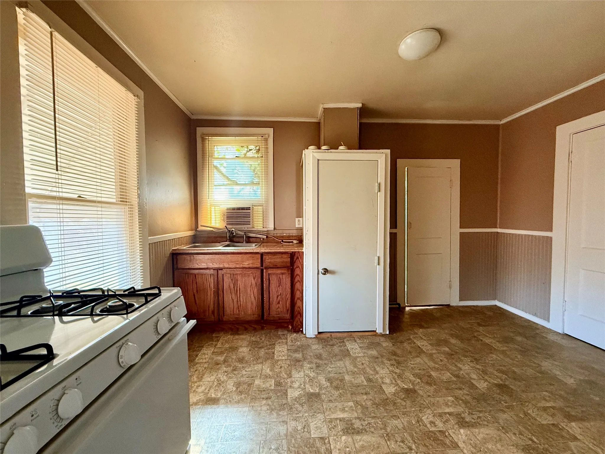 Kitchen featuring white range with gas cooktop, sink, and ornamental molding