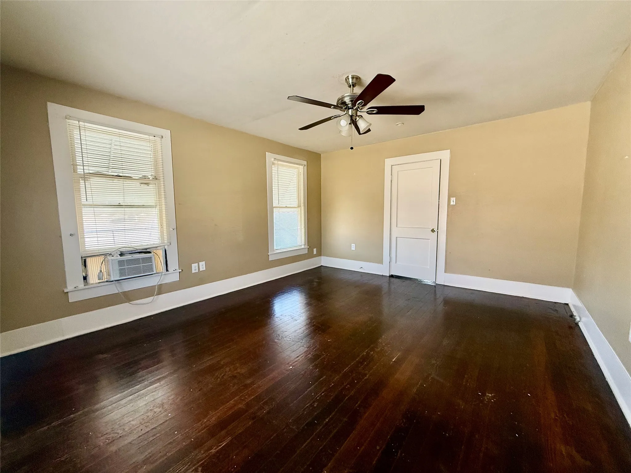 Spare room with dark hardwood / wood-style flooring, cooling unit, a healthy amount of sunlight, and ceiling fan