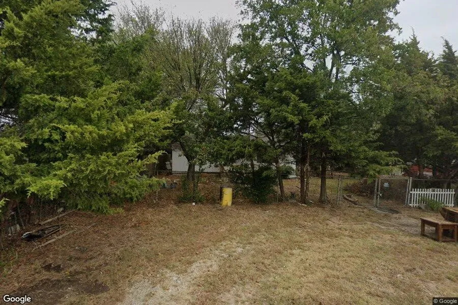 Expansive exterior featuring mature trees, a chain-link fence, and a white picket fence