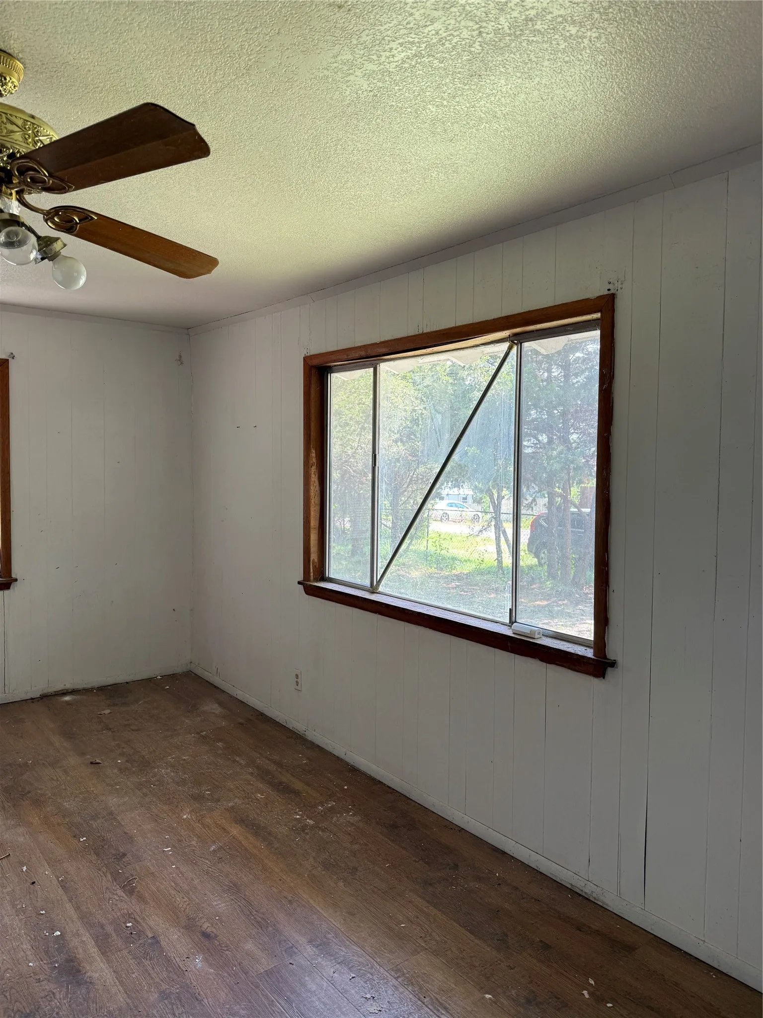 Wood-finish flooring with white paneled walls and wood-trimmed windows