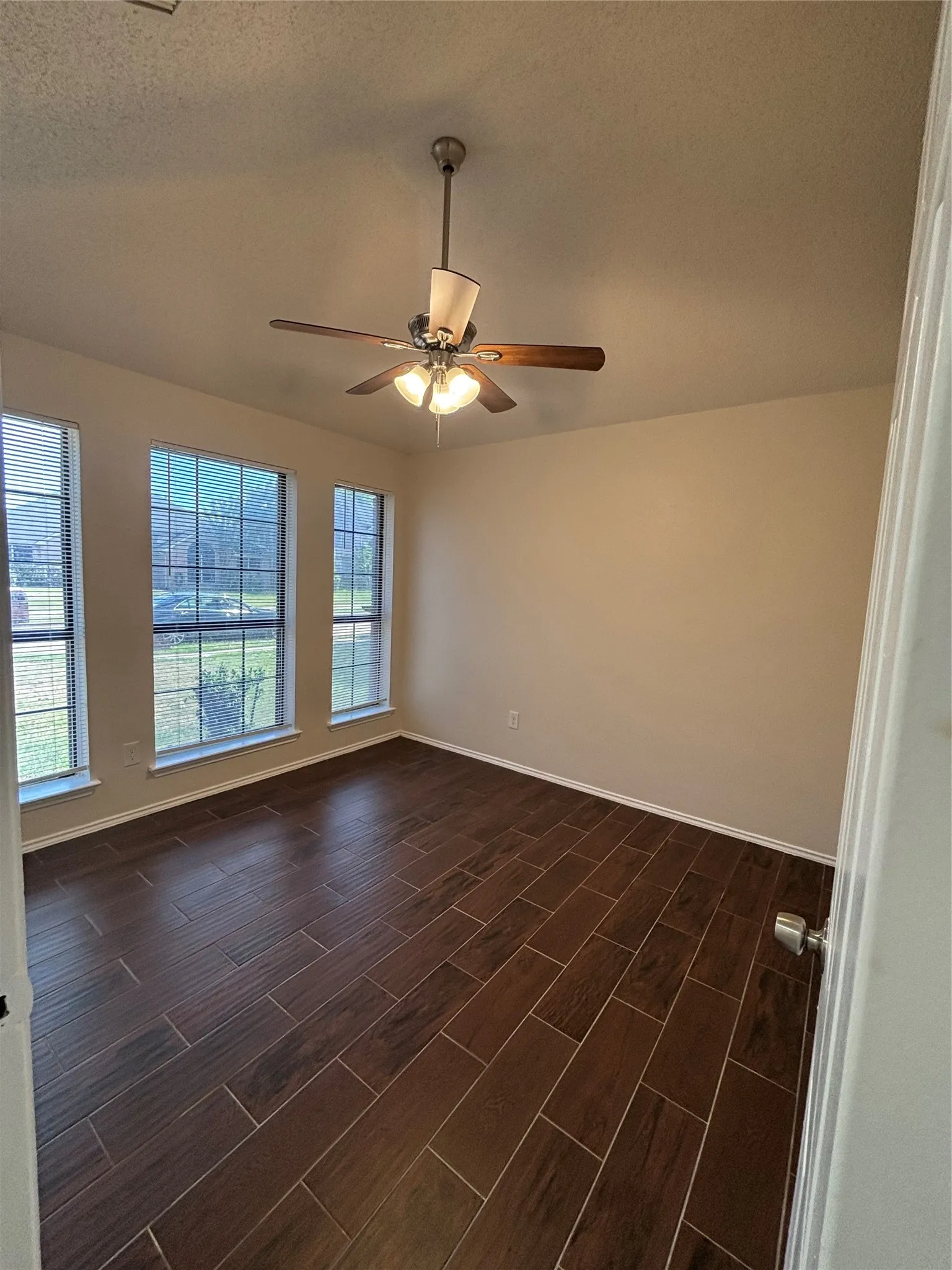 Unfurnished room featuring a textured ceiling, wood tiled floors, and a ceiling fan