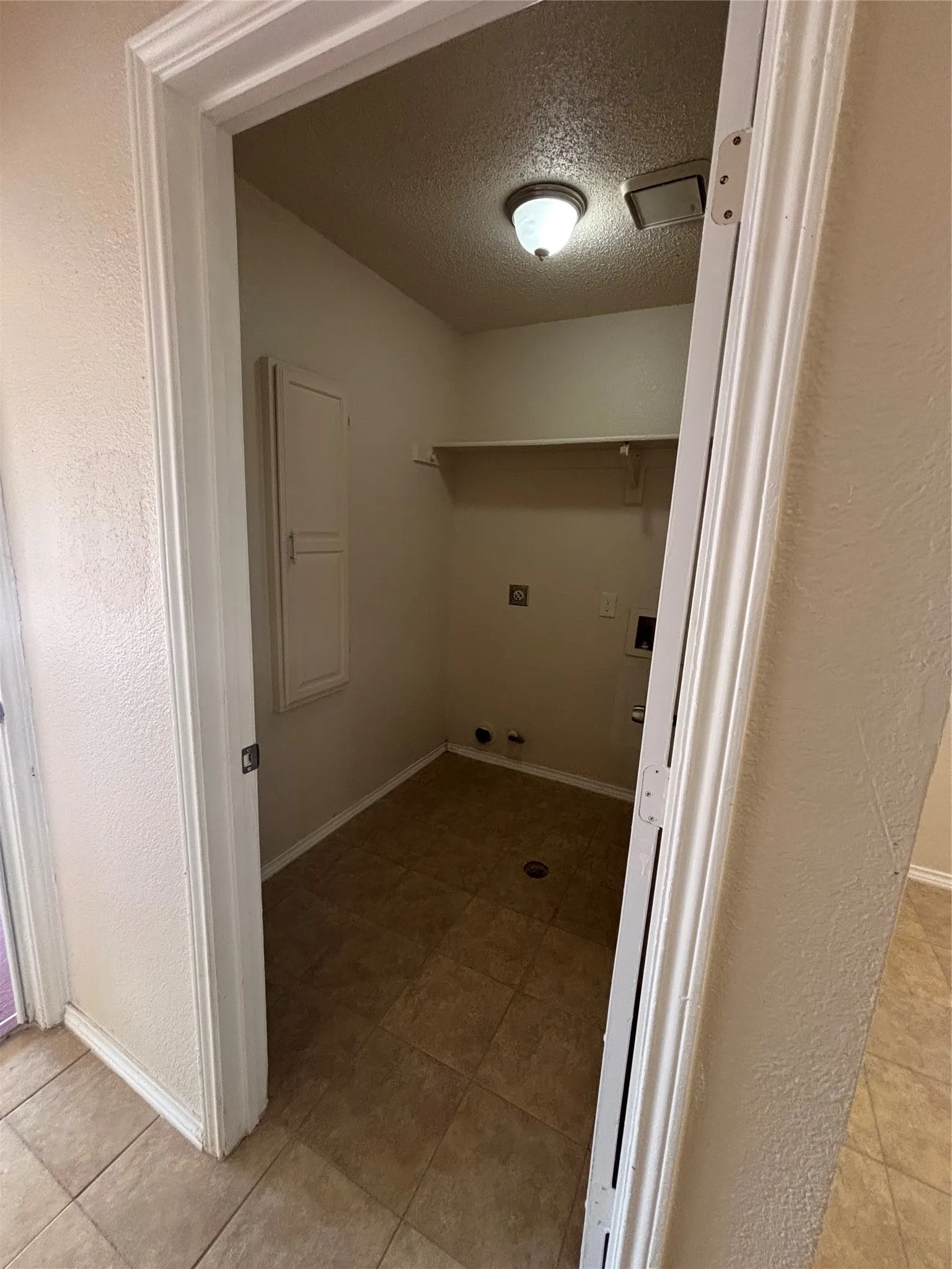 Laundry room featuring a textured ceiling, a textured wall, light tile patterned floors, and washer​​‌​​​​‌​​‌‌​‌‌​​​‌‌​‌​‌​‌​​​‌​​ hookup