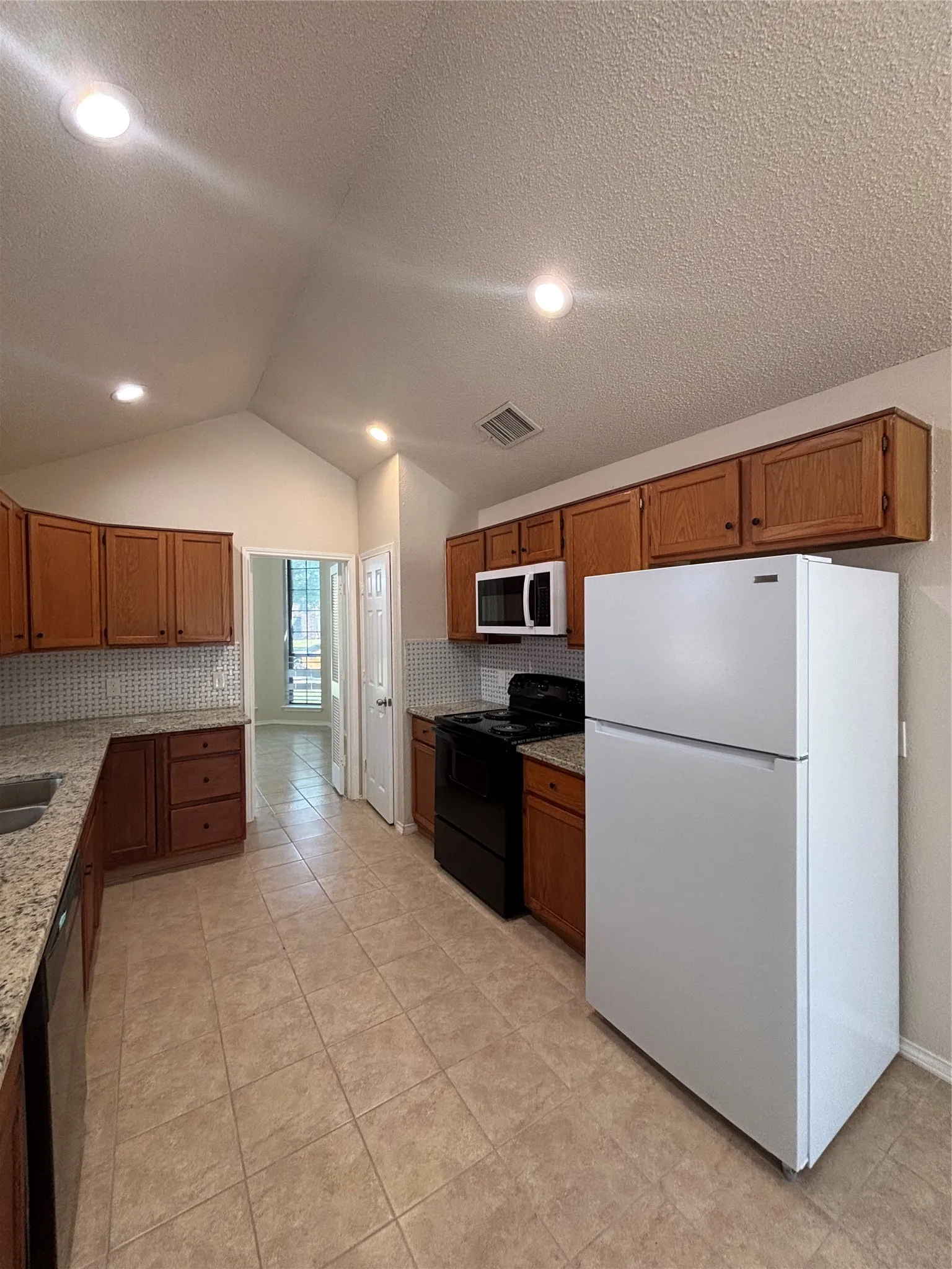 Kitchen featuring white appliances, backsplash, wood finish cabinetry, light stone countertops, and recessed lighting