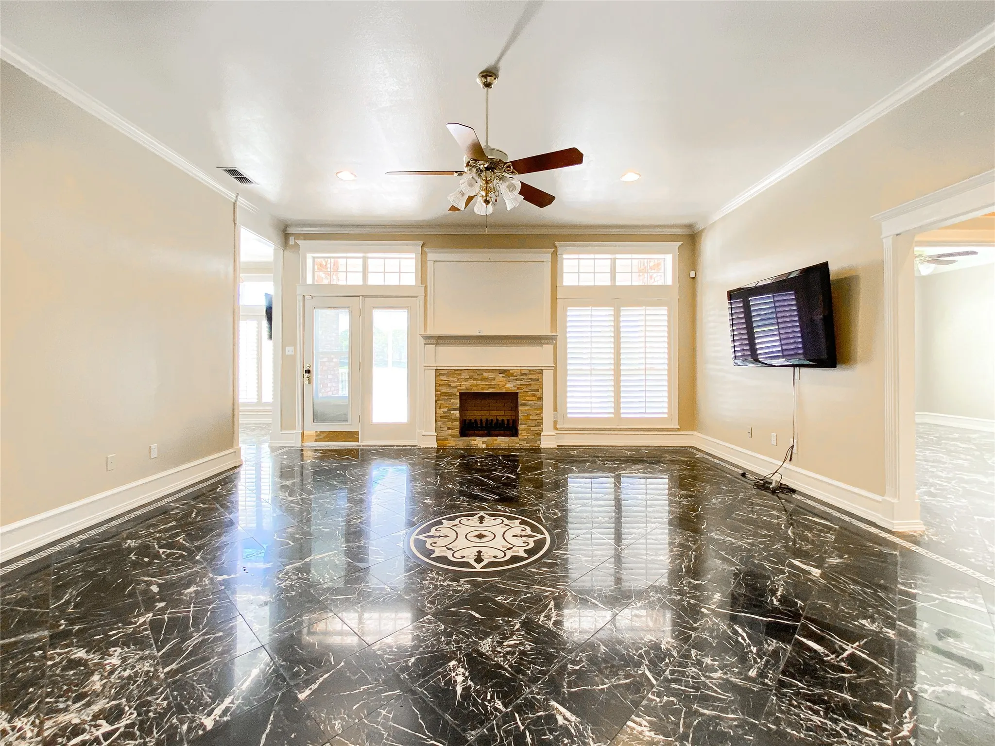 MAIN living room with ceiling fan, ornamental molding, a fireplace, and dark marble finish floors