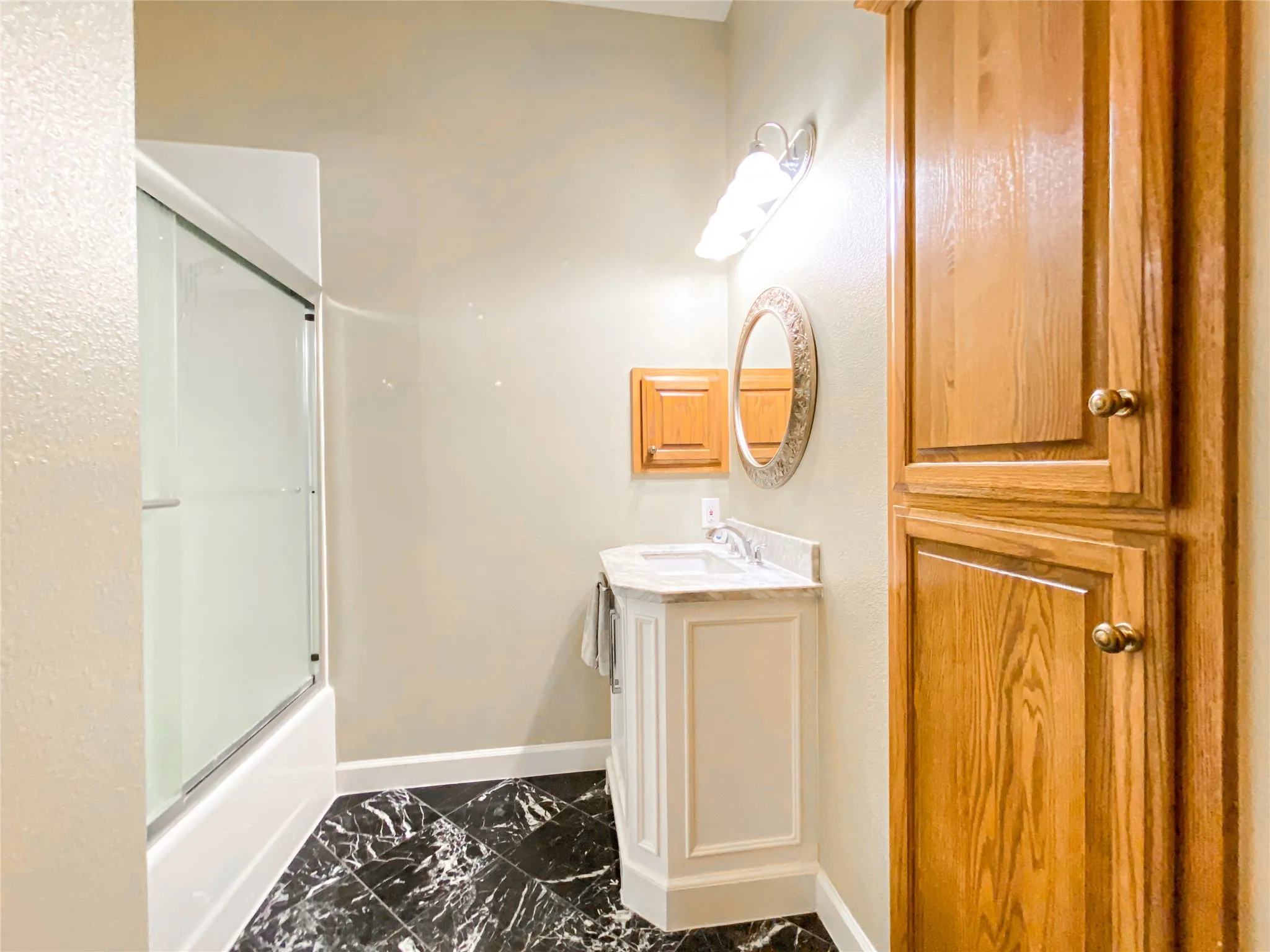 OFFICE/5TH BEDROOM Bathroom featuring vanity, enclosed tub / shower combo, and dark marble finish flooring