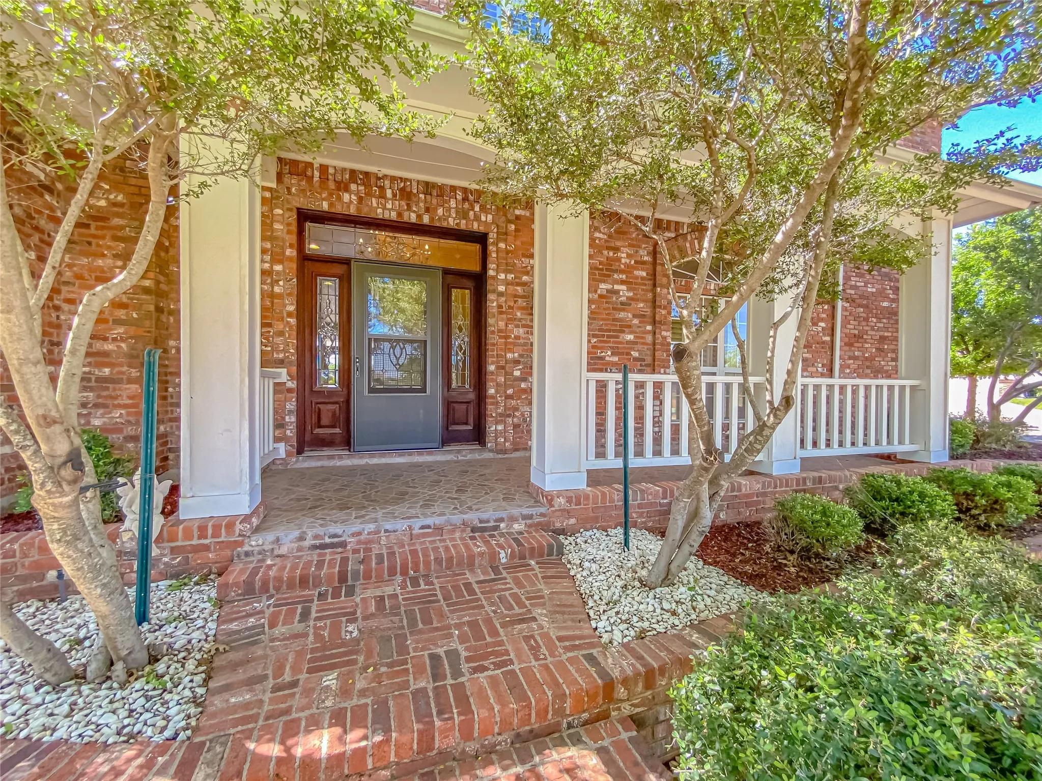 Entrance to property featuring covered porch and brick siding