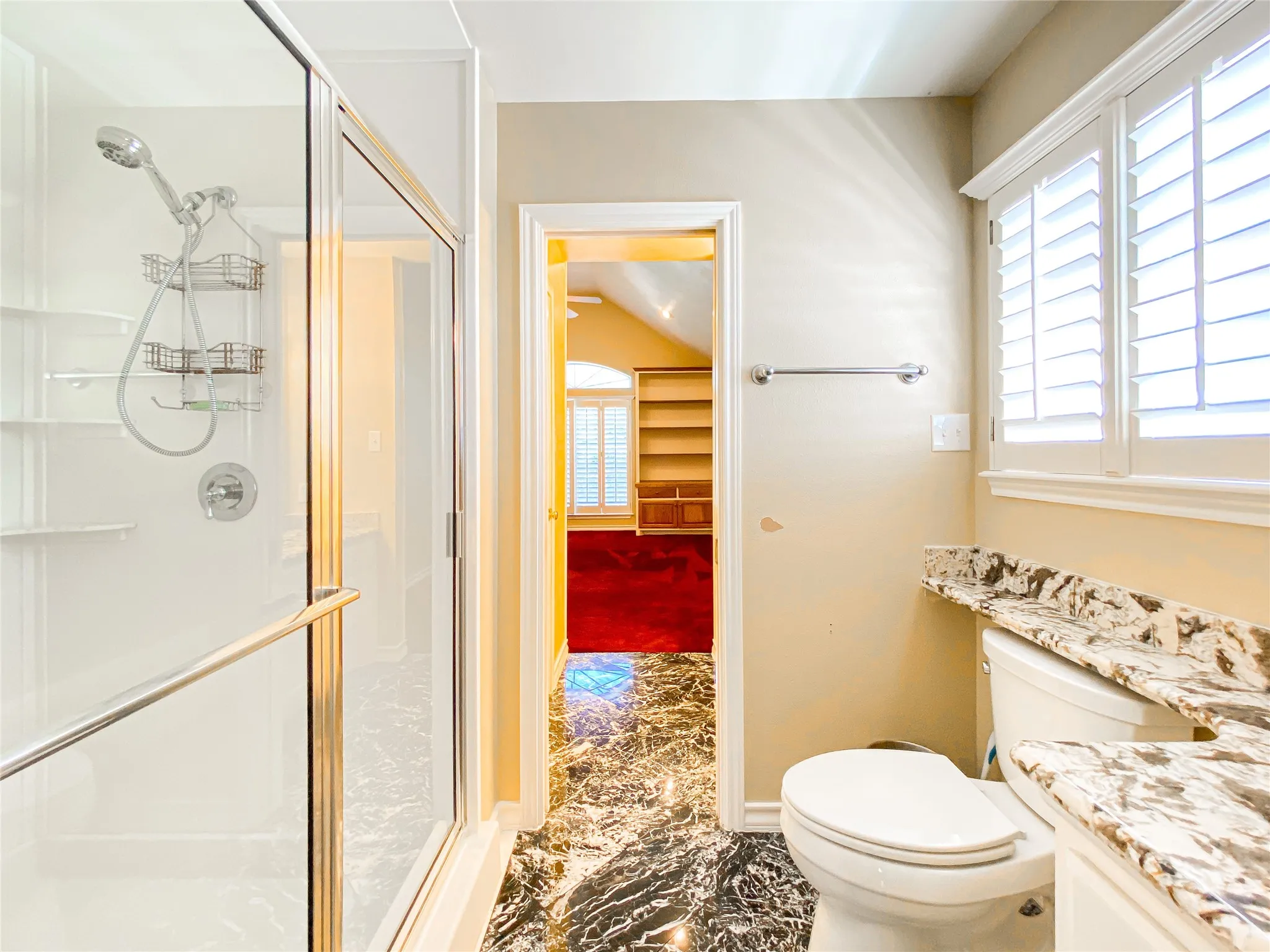 Bathroom featuring vanity, a shower stall, light marble finish floors, and lofted ceiling