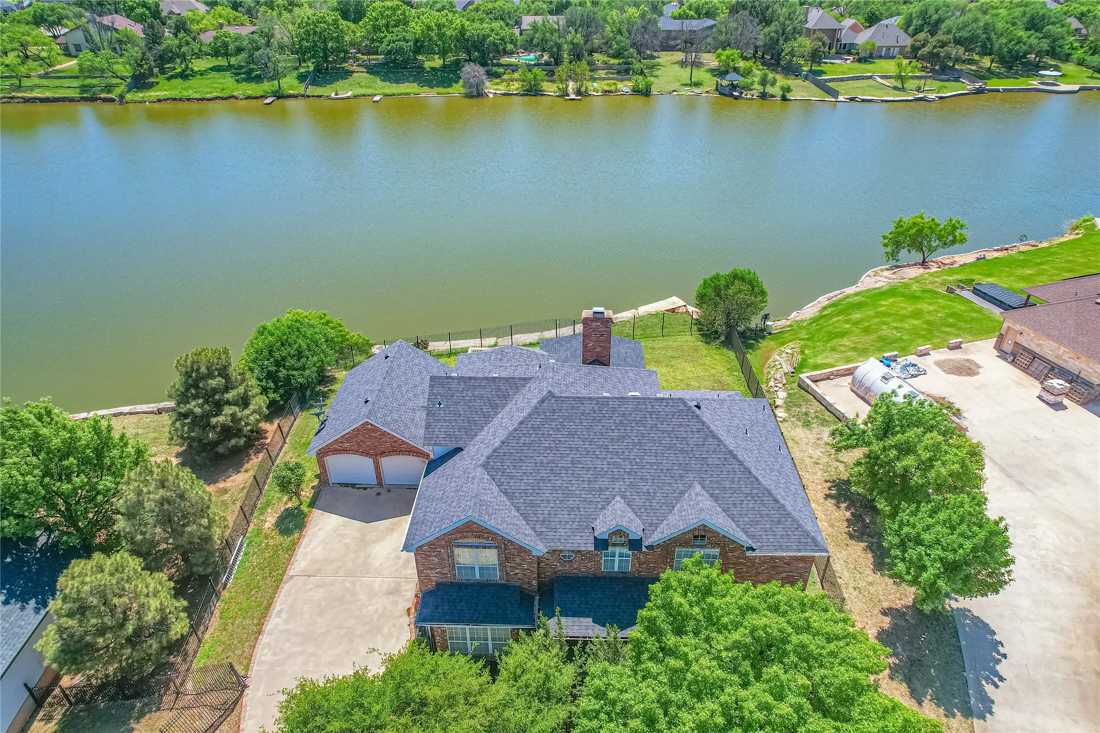Aerial view of property and surrounding area featuring a nearby body of water and a tree filled landscape