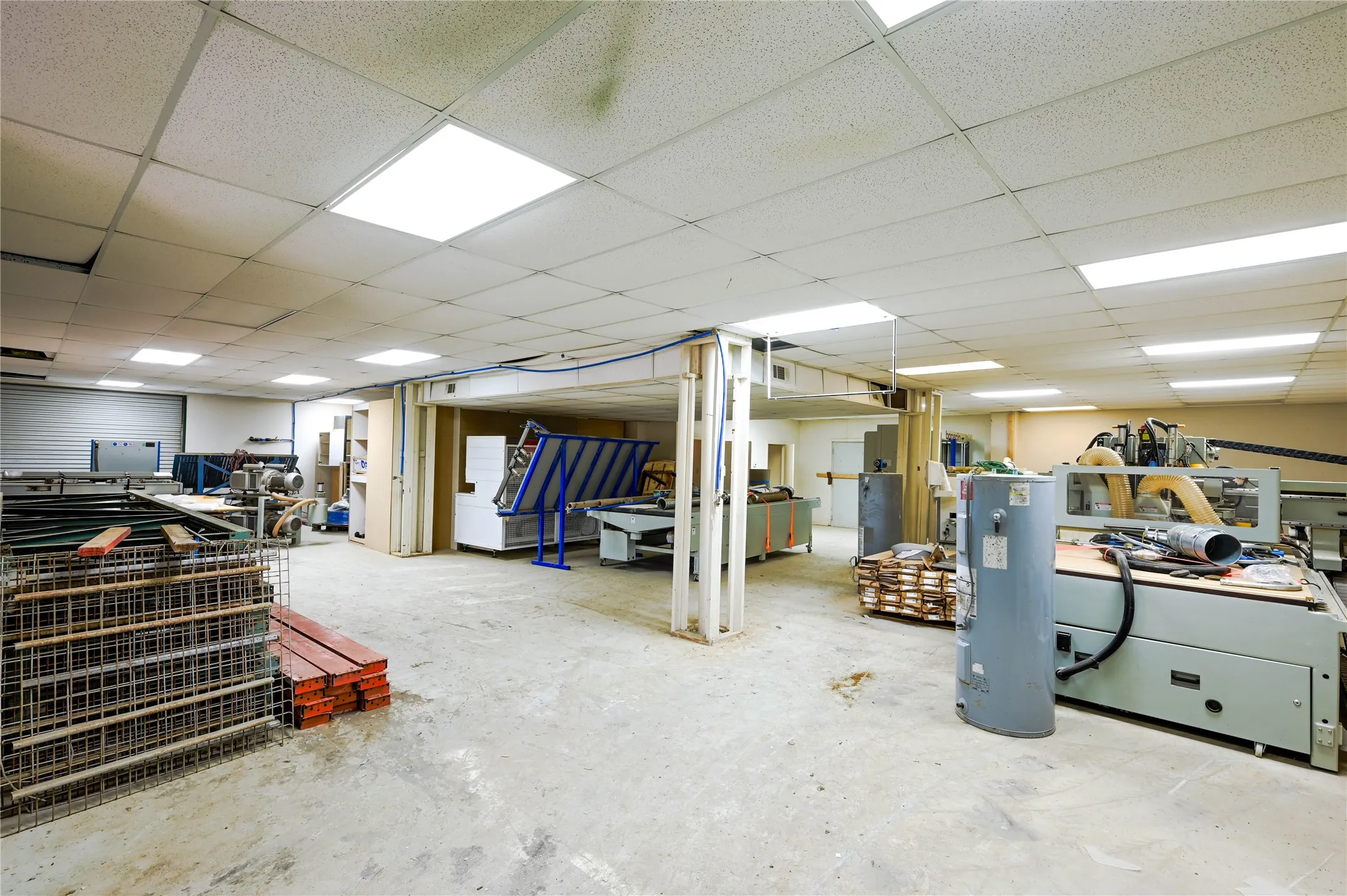 Open-concept commercial space featuring a drop ceiling with integrated lighting, concrete flooring, and partial wall framing for custom build-out