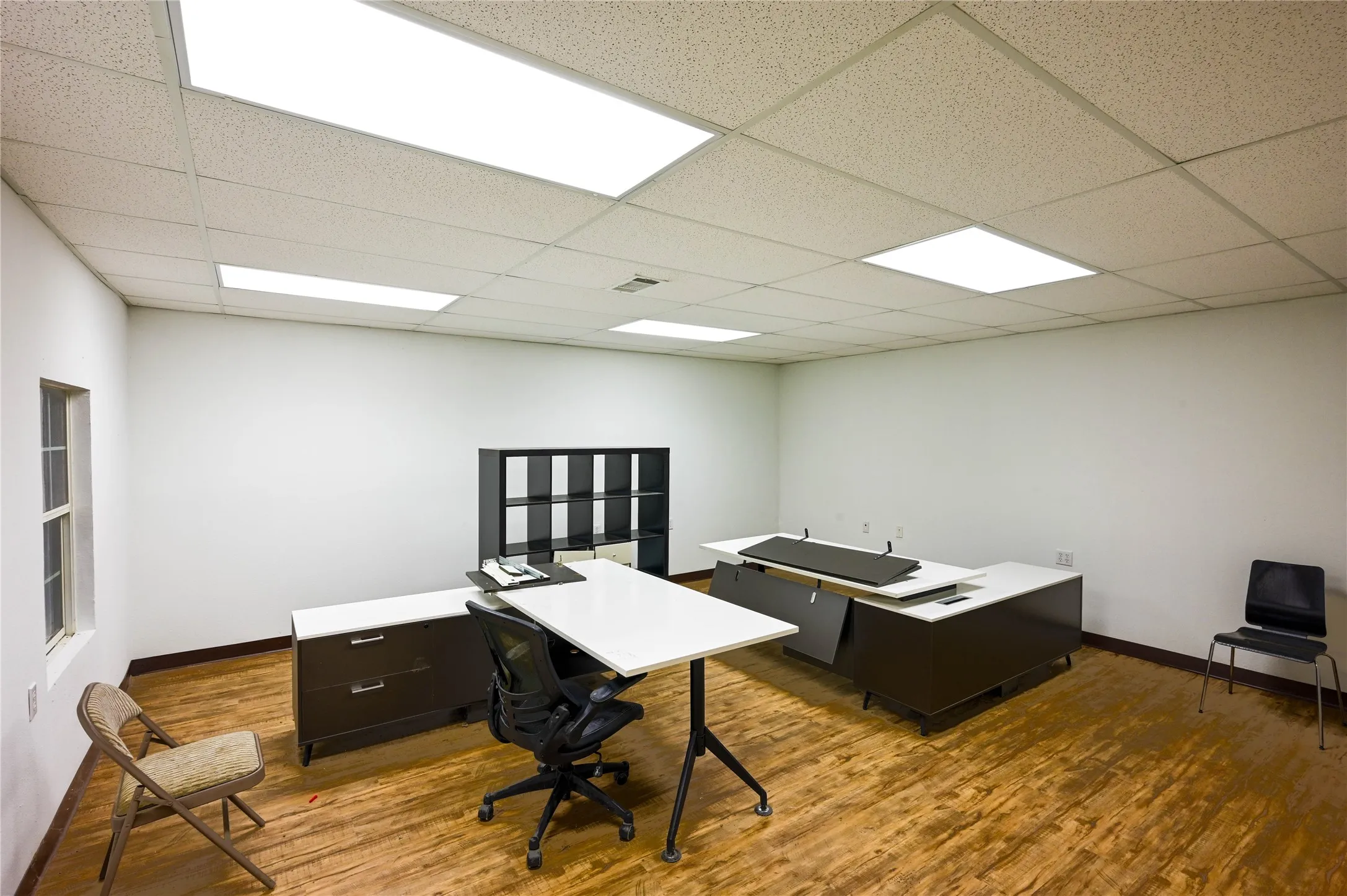Spacious interior featuring wood-finish flooring, white walls, and a drop ceiling with integrated rectangular lighting