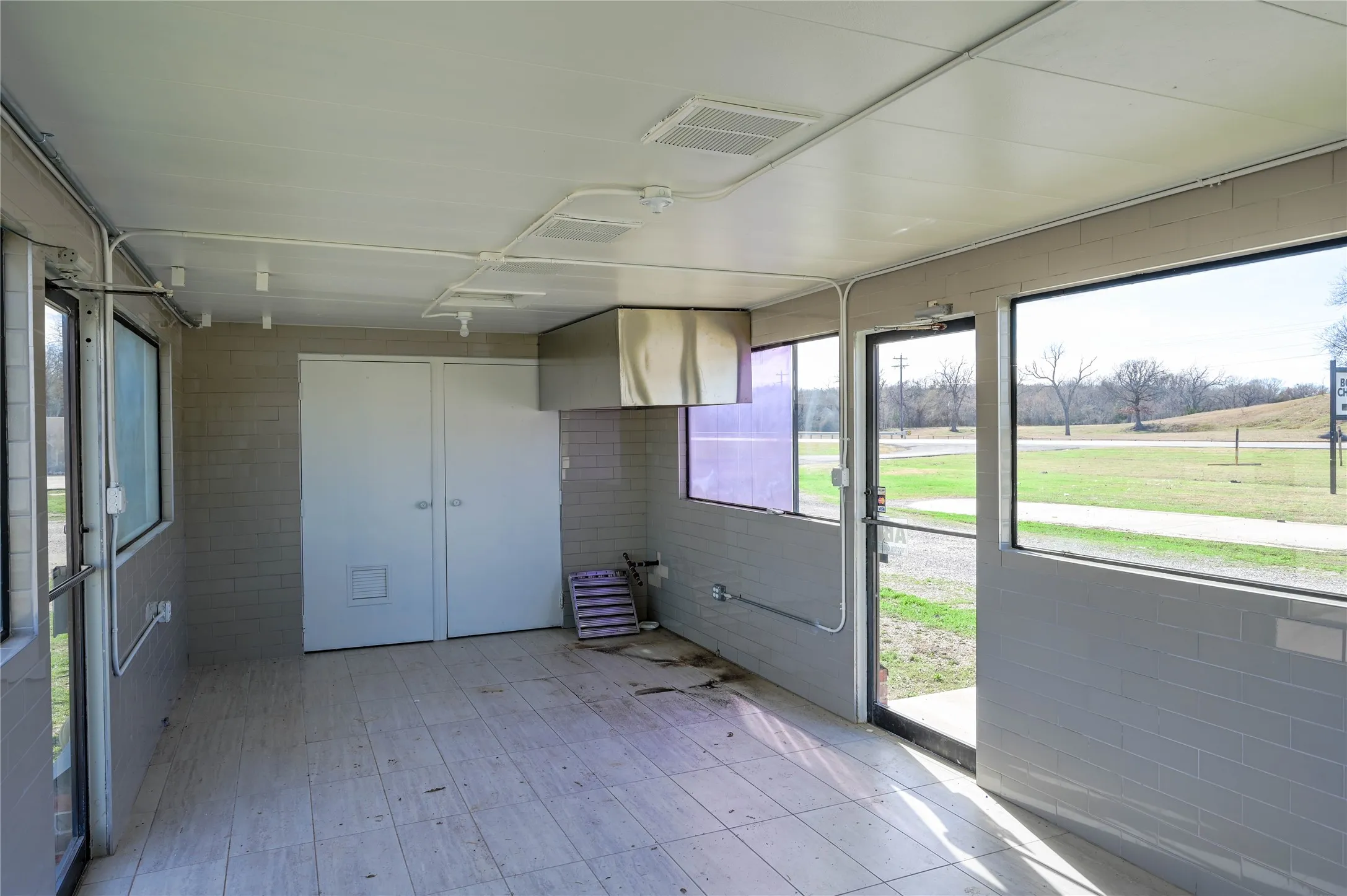 Enclosed space featuring multiple windows, a glass-paneled door, and tile flooring