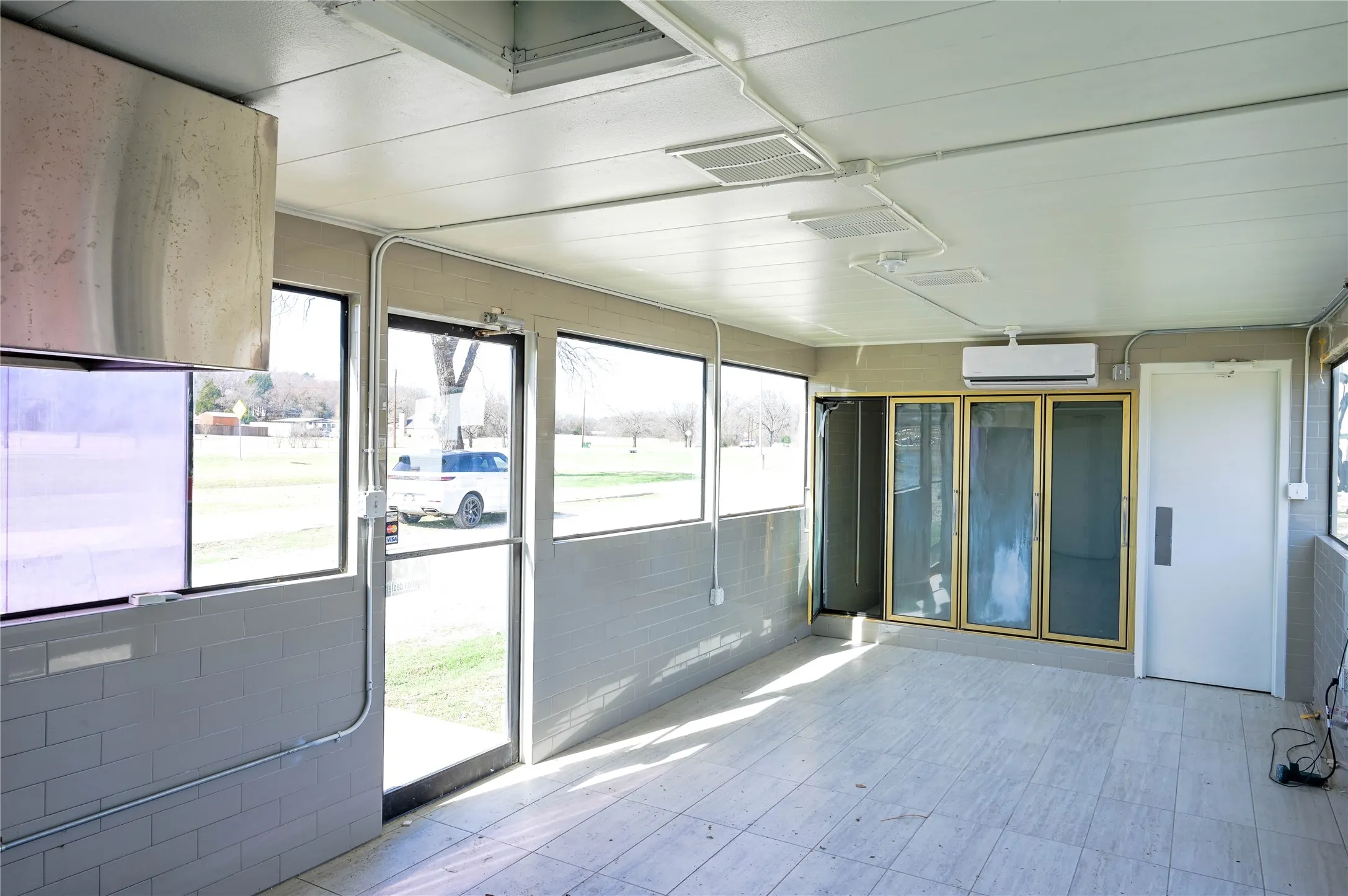 Bright interior space featuring a glass entry door, multiple windows, and a light-toned tile floor